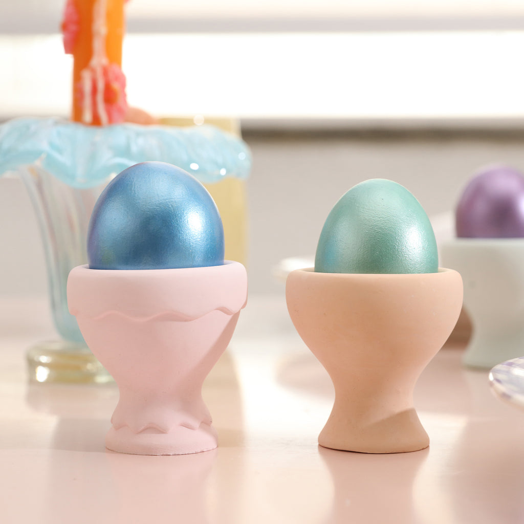 Two colorful egg cups with vibrant Easter eggs on top.