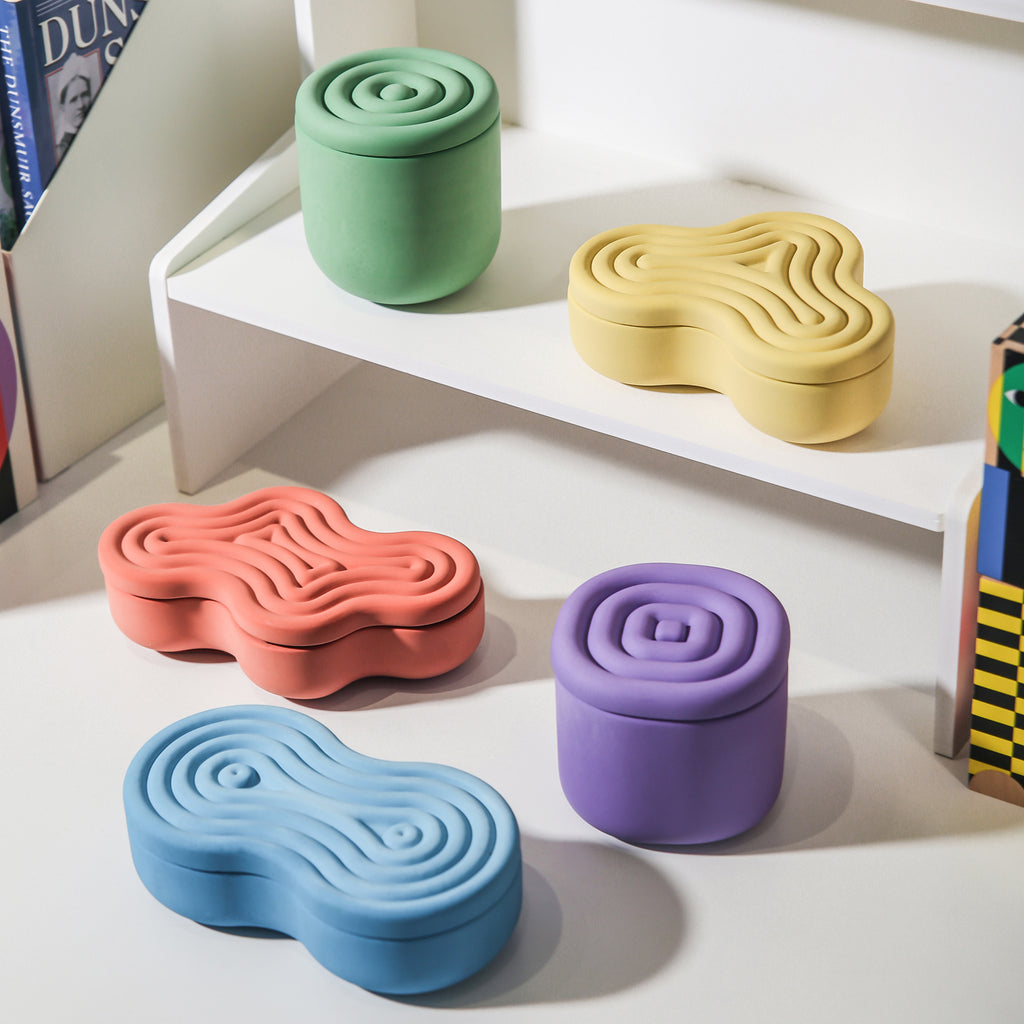 Five candle jars with different wriggling stripes placed on a bookshelf - Boowan Nicole