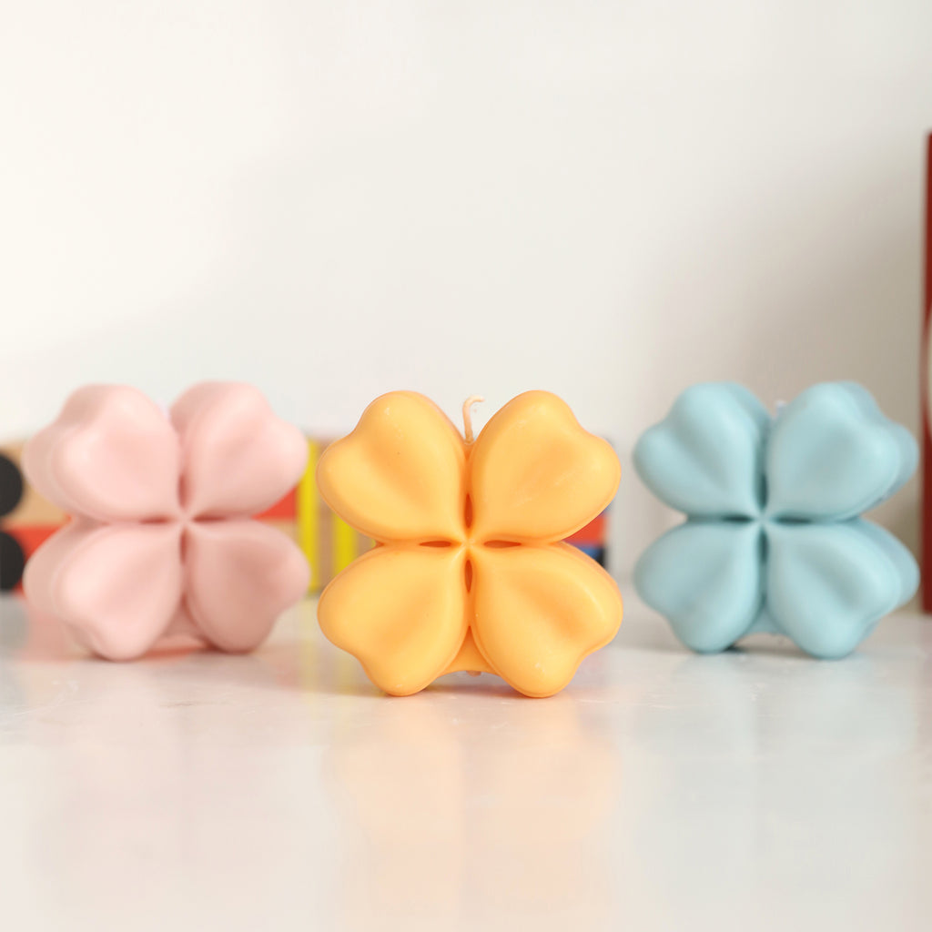 Three pink, yellow and blue Four-Leaf Clover Candles are placed on the table-Boowan Nicole