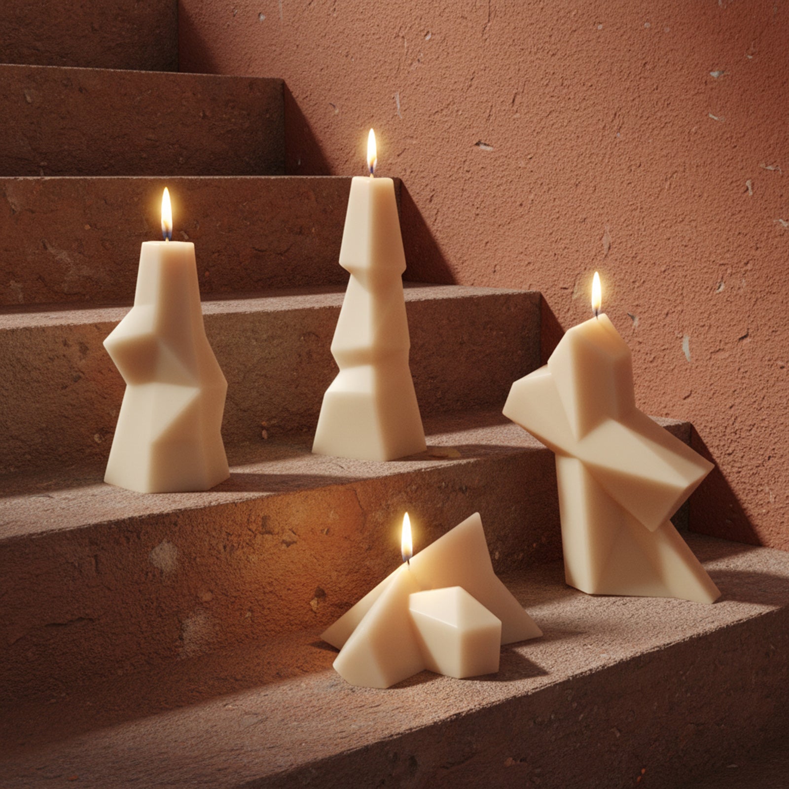 Abstract geometric pillar candles in warm ivory wax displayed on terracotta steps, showing the sculptural shapes made with our silicone molds - Boowan Nicole