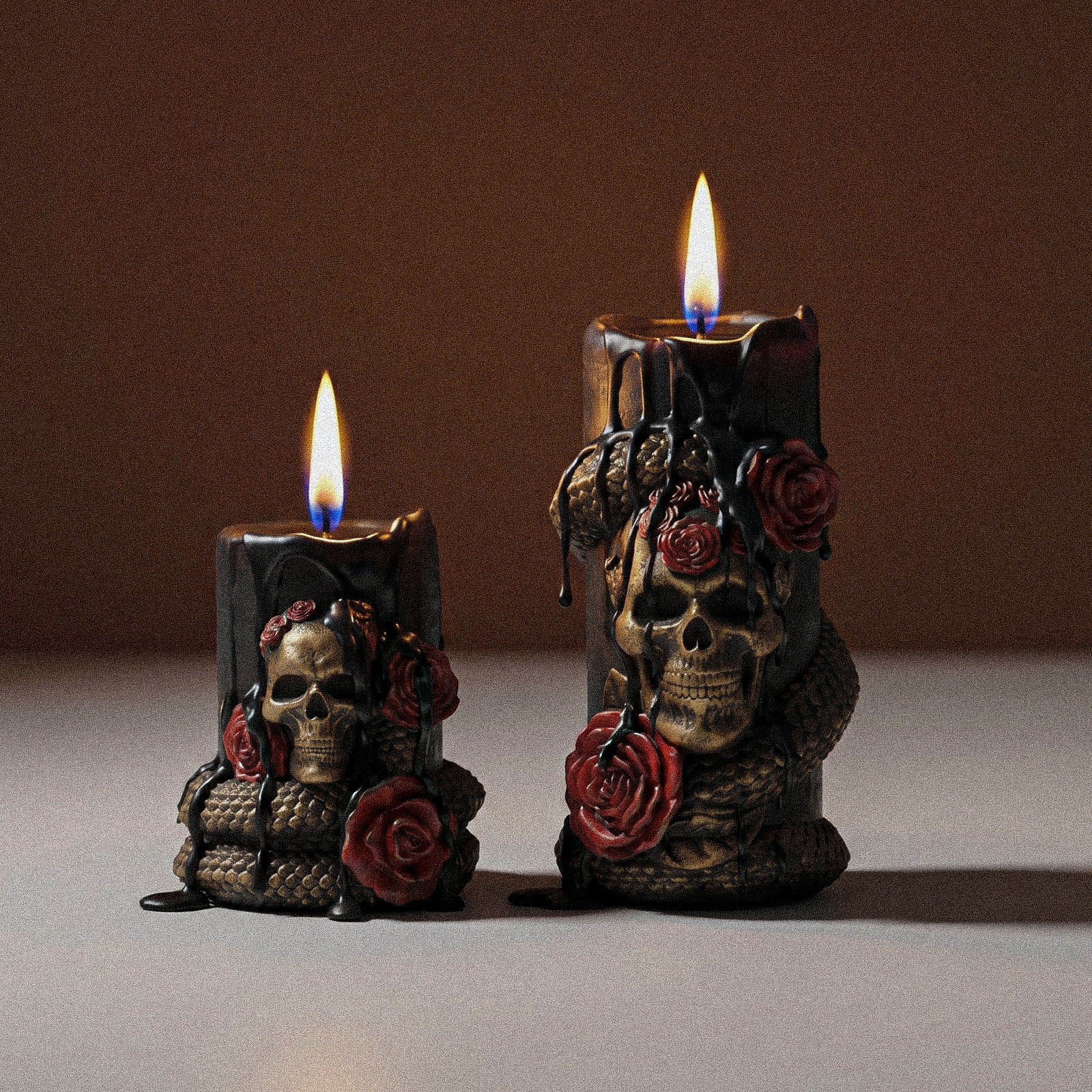Two sizes lit Venom & Roses gothic pillar candles with skull, coiled serpent and red rose relief minimalist neutral studio shot - Boowan Nicole