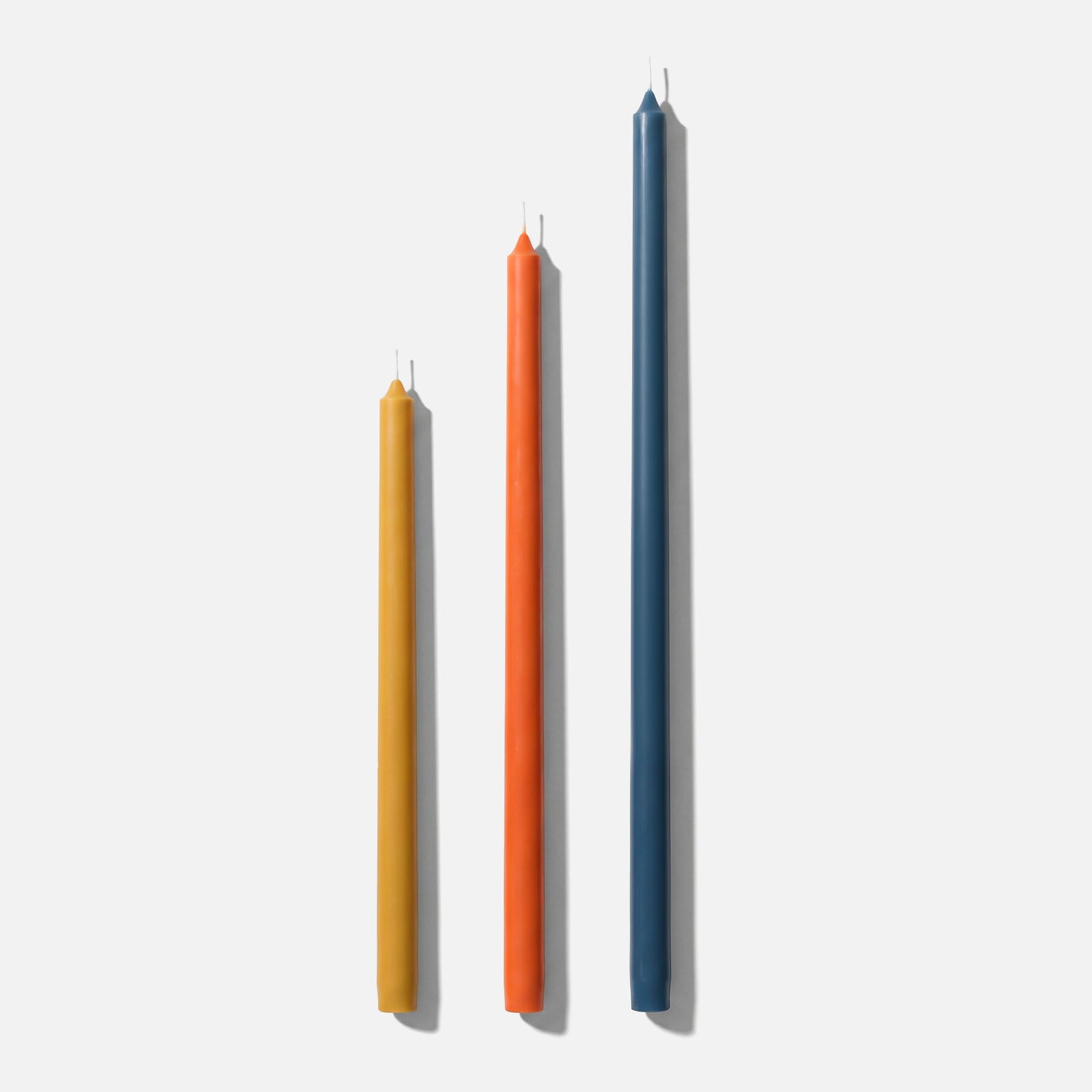 Tall Slim Taper Candles in Yellow, Orange, and Blue on White Background - Boowan Nicole