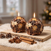 Two lit rustic spice‑themed spherical candles on wooden slab with cinnamon and star anise Christmas decor - Boowan Nicole