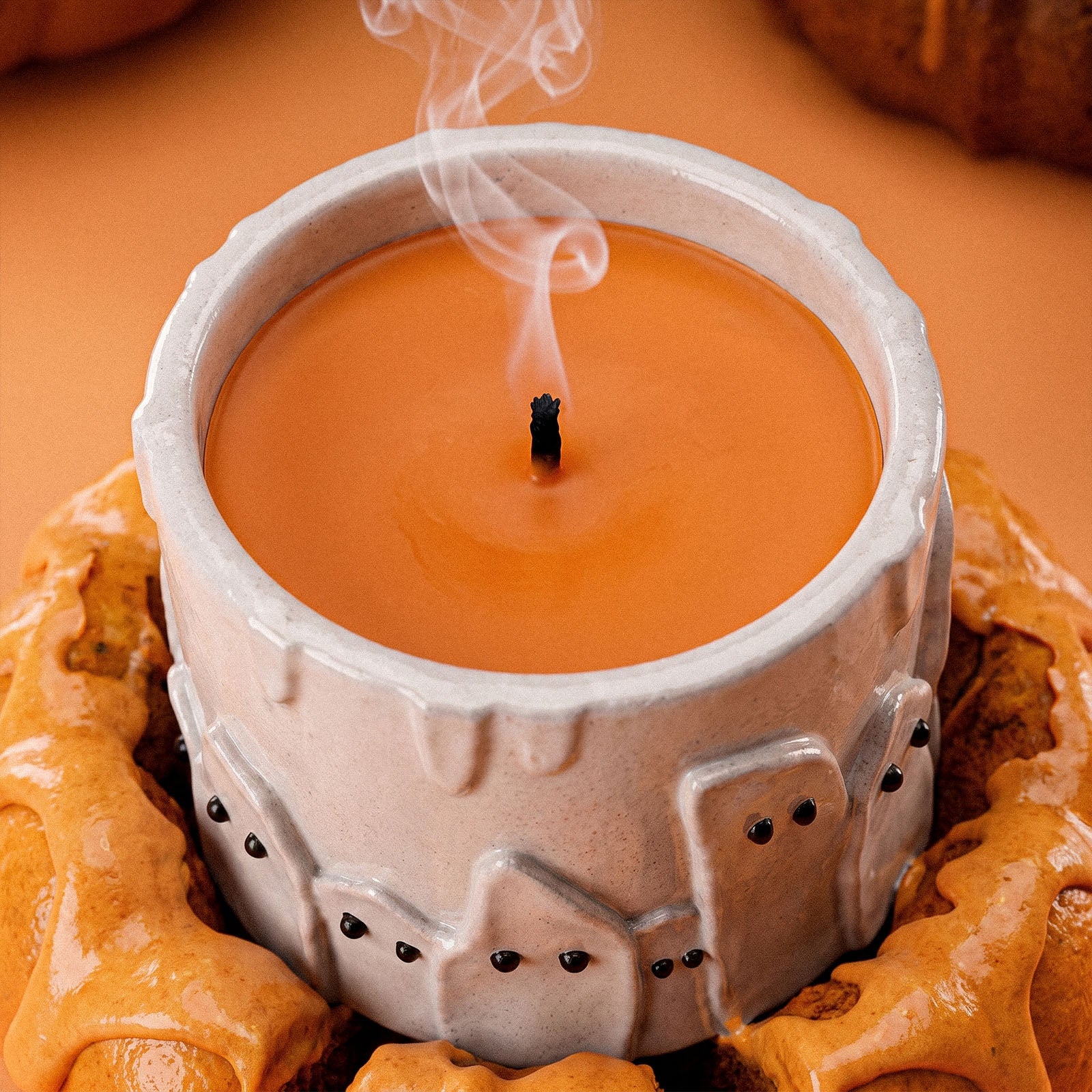 Top view of ghost cake candle jar filled with orange scented candle wax, candle wick smoking gently - Boowan Nicole