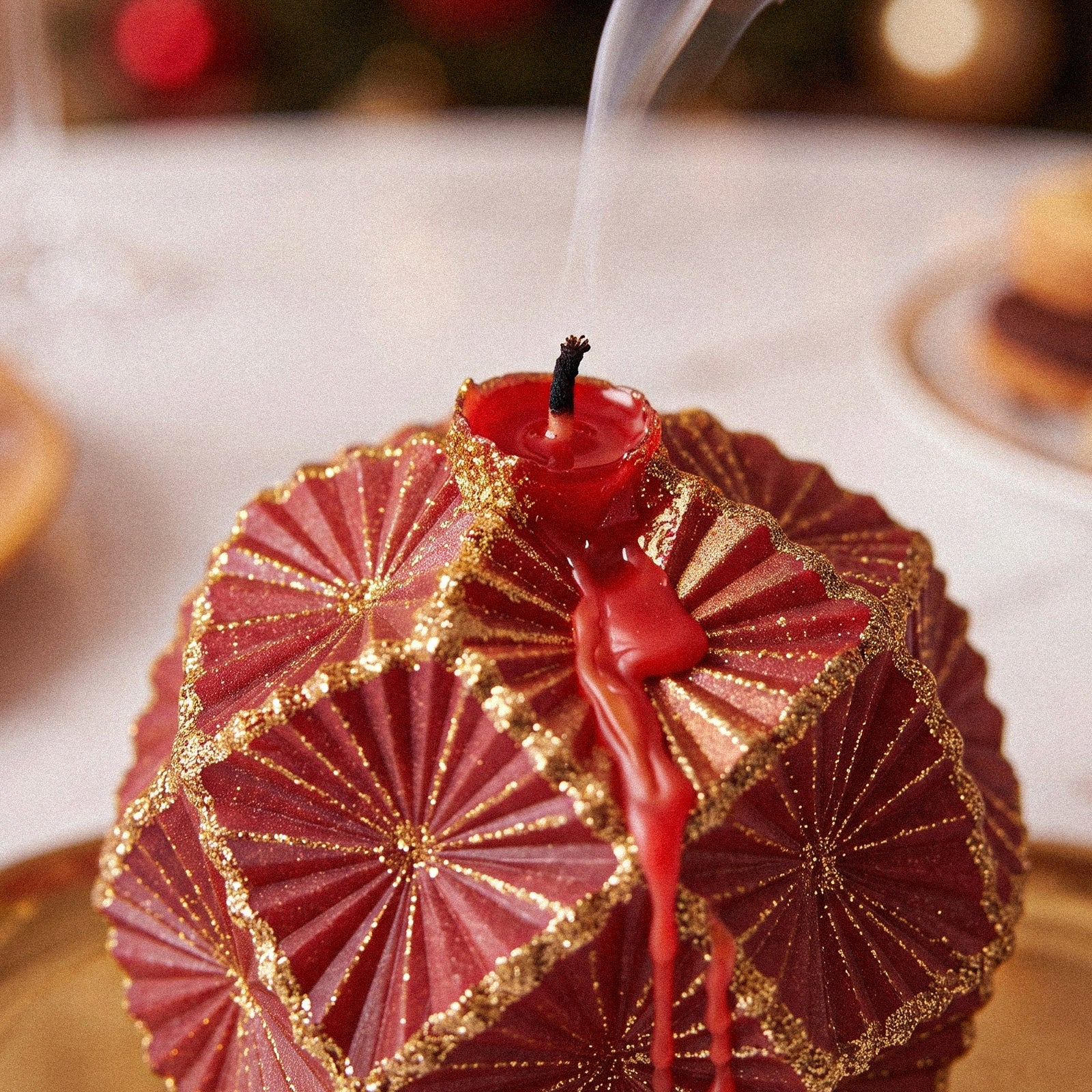 Close‑up of burning red ornament candle with melted wax dripping down textured surface - Boowan Nicole