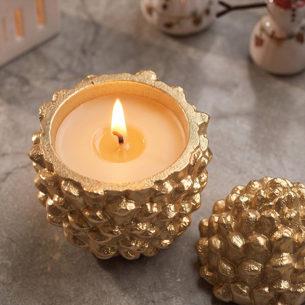 Lit gold textured Little Woodland Pinecone candle jar with matching lid aside on grey marble surface winter interior shot - Boowan Nicole