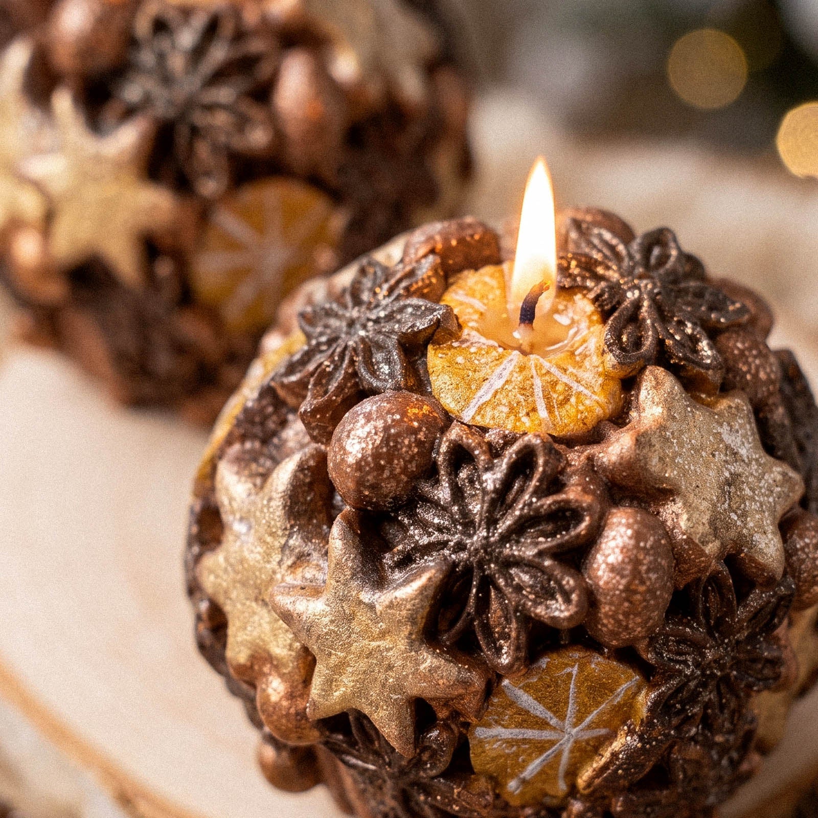 Close‑up of burning spherical candle, detailed embossed star, flower and dried citrus textures - Boowan Nicole