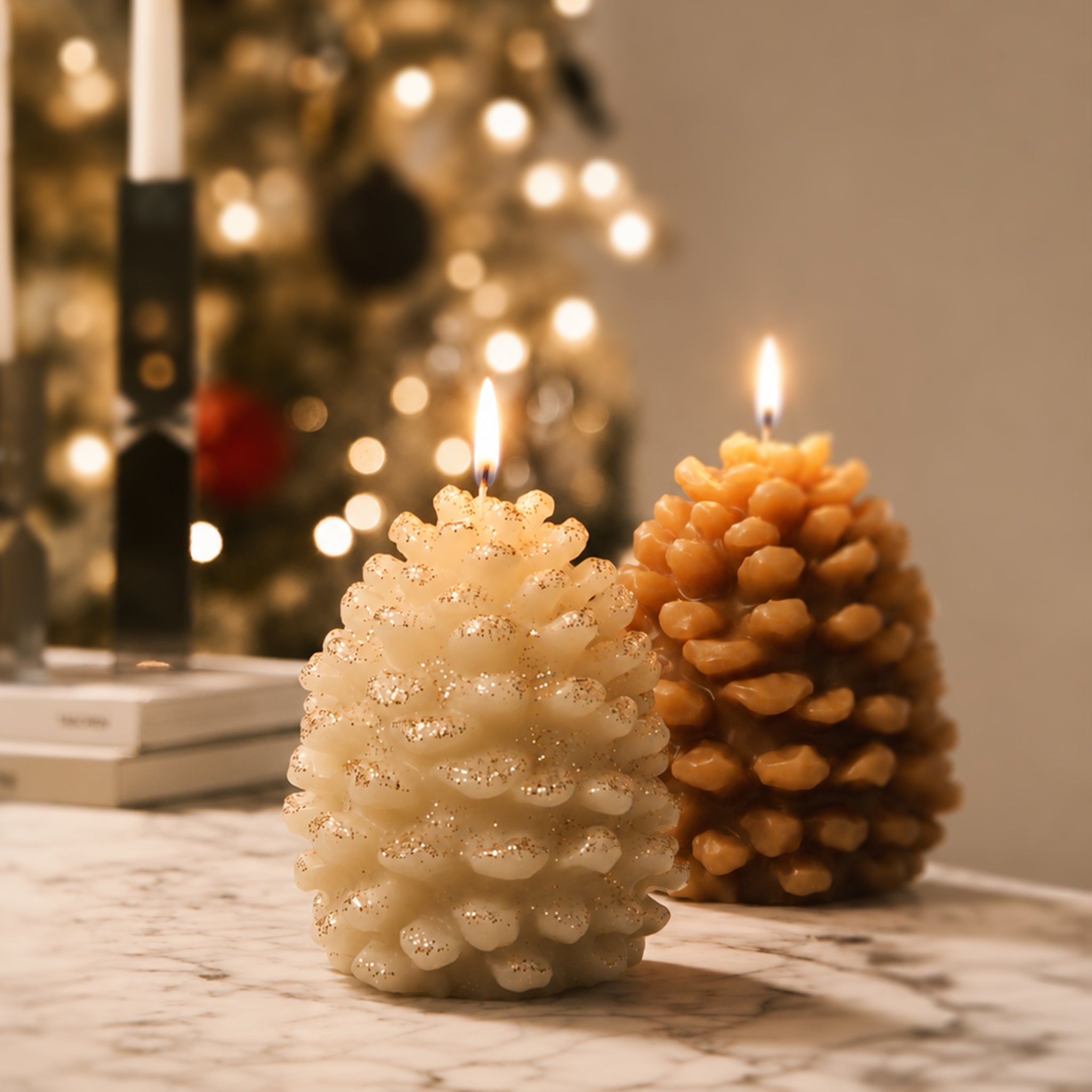 Two lit winter pinecone pillar candles in cream and caramel tones marble table Christmas bokeh background styling - Boowan Nicole

