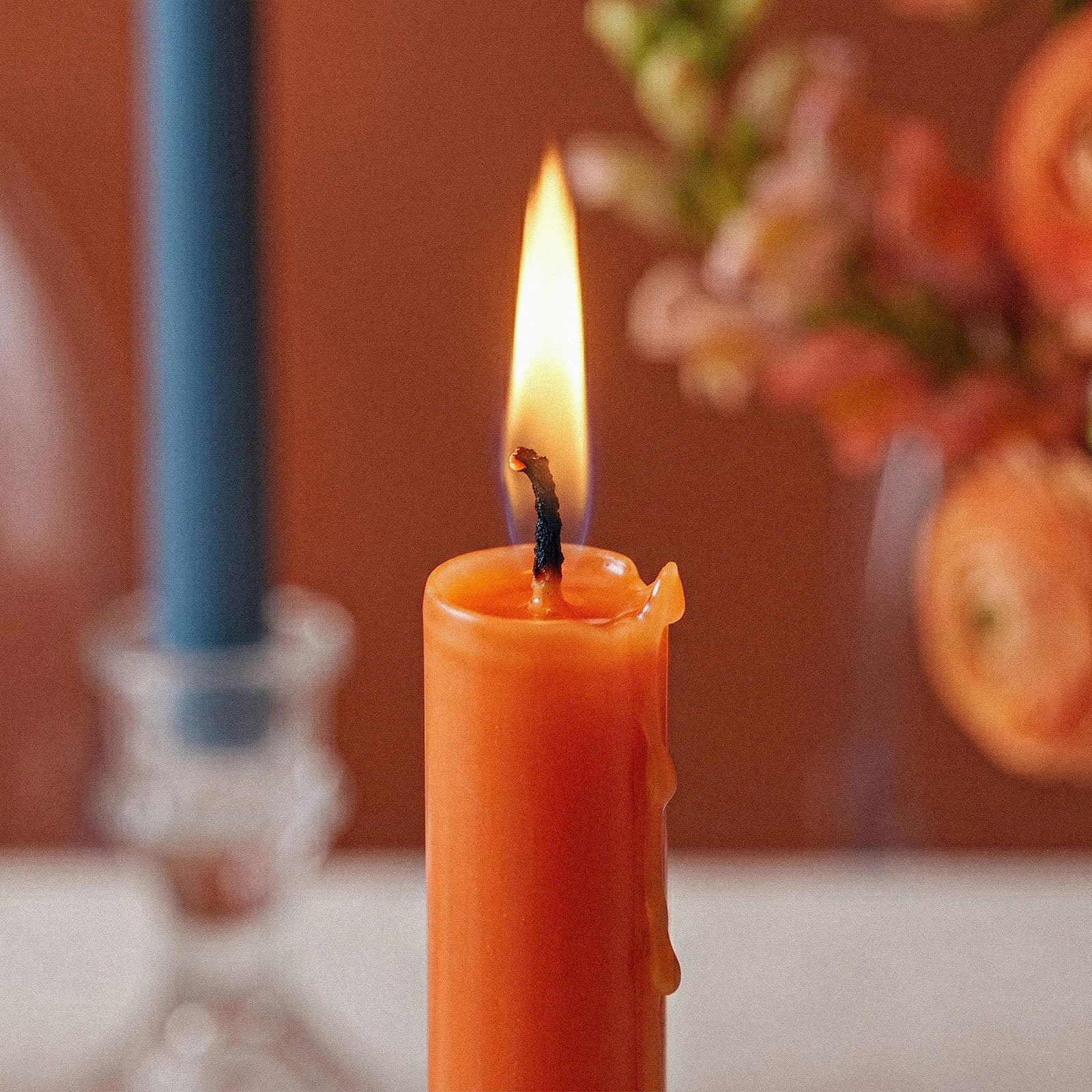 Close-up of Lit Orange Tall Slim Taper Candle with Wax Drips - Boowan Nicole