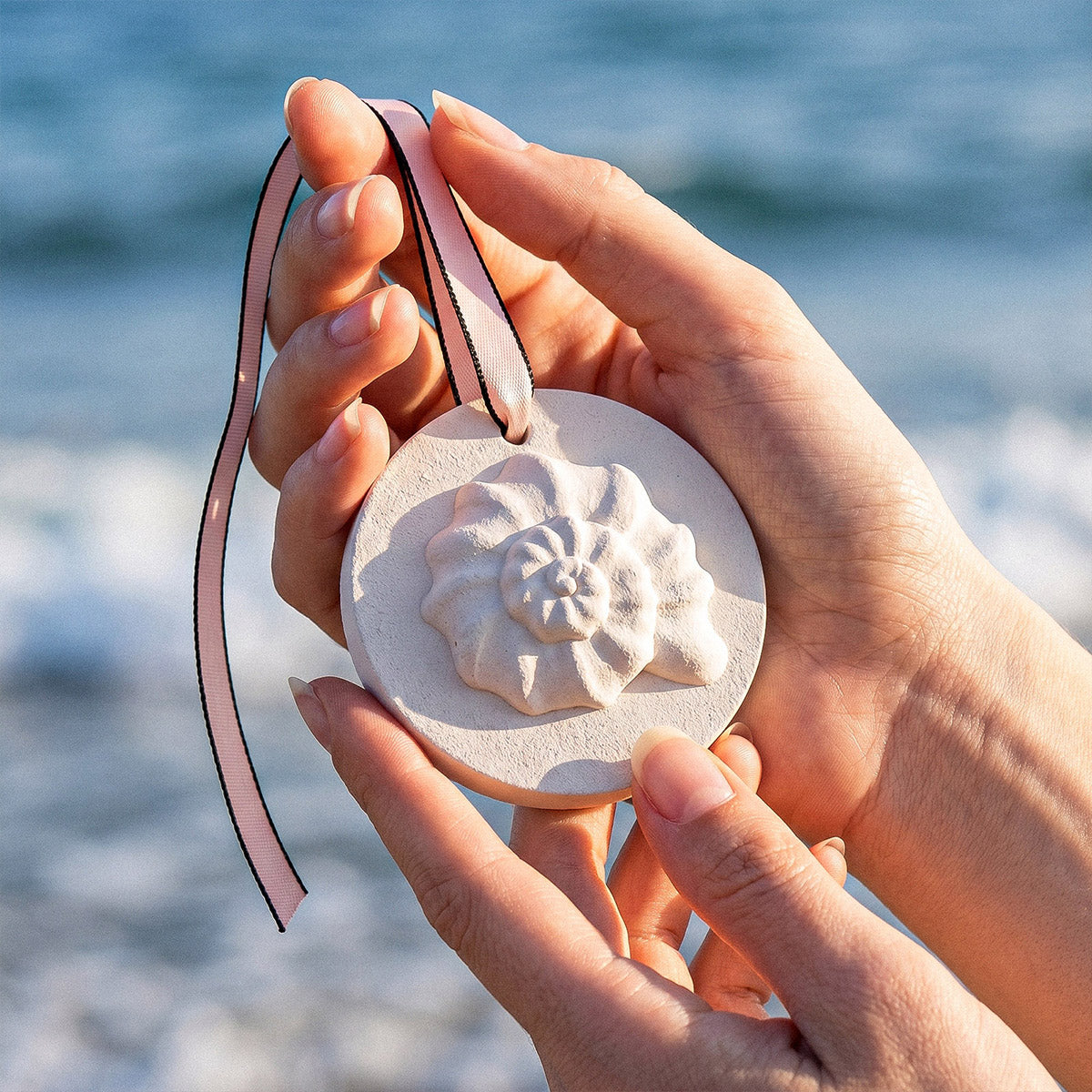 Hand Holding Flower-shaped Scent Hanger with Ocean View Background - Boowan Nicole