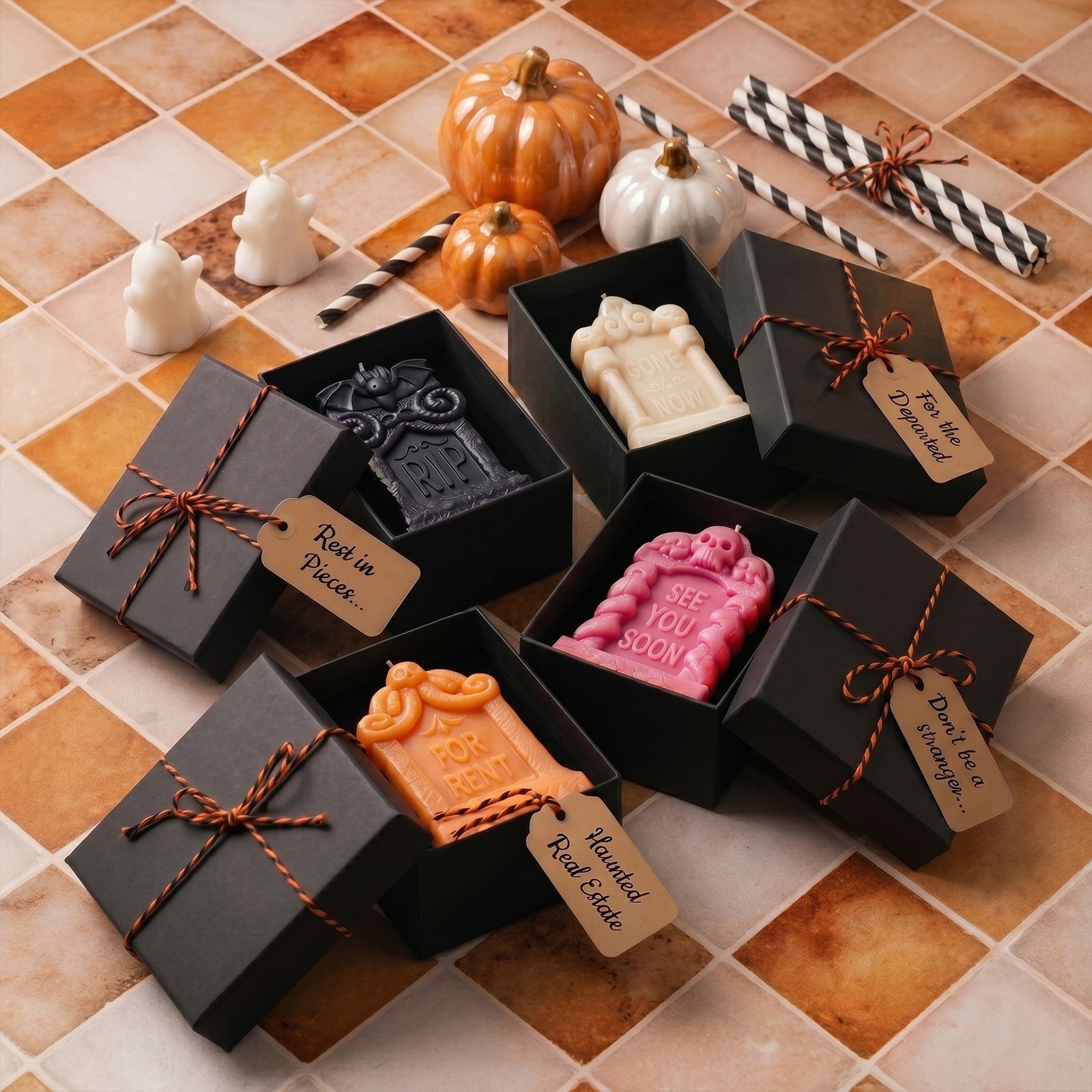Assorted tombstone candles packed in black kraft gift boxes with funny Halloween tags orange tile flat lay gift set shot - Boowan Nicole