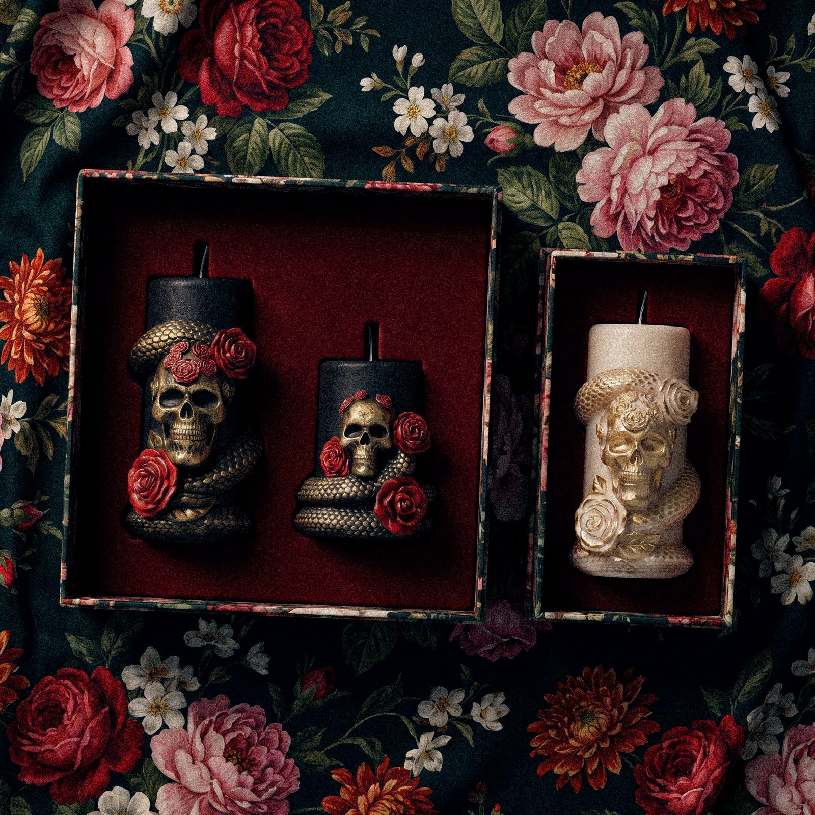 Gift box display of assorted Venom & Roses pillar candles, black goth finish and cream gold finish on vintage floral fabric flat lay - Boowan Nicole