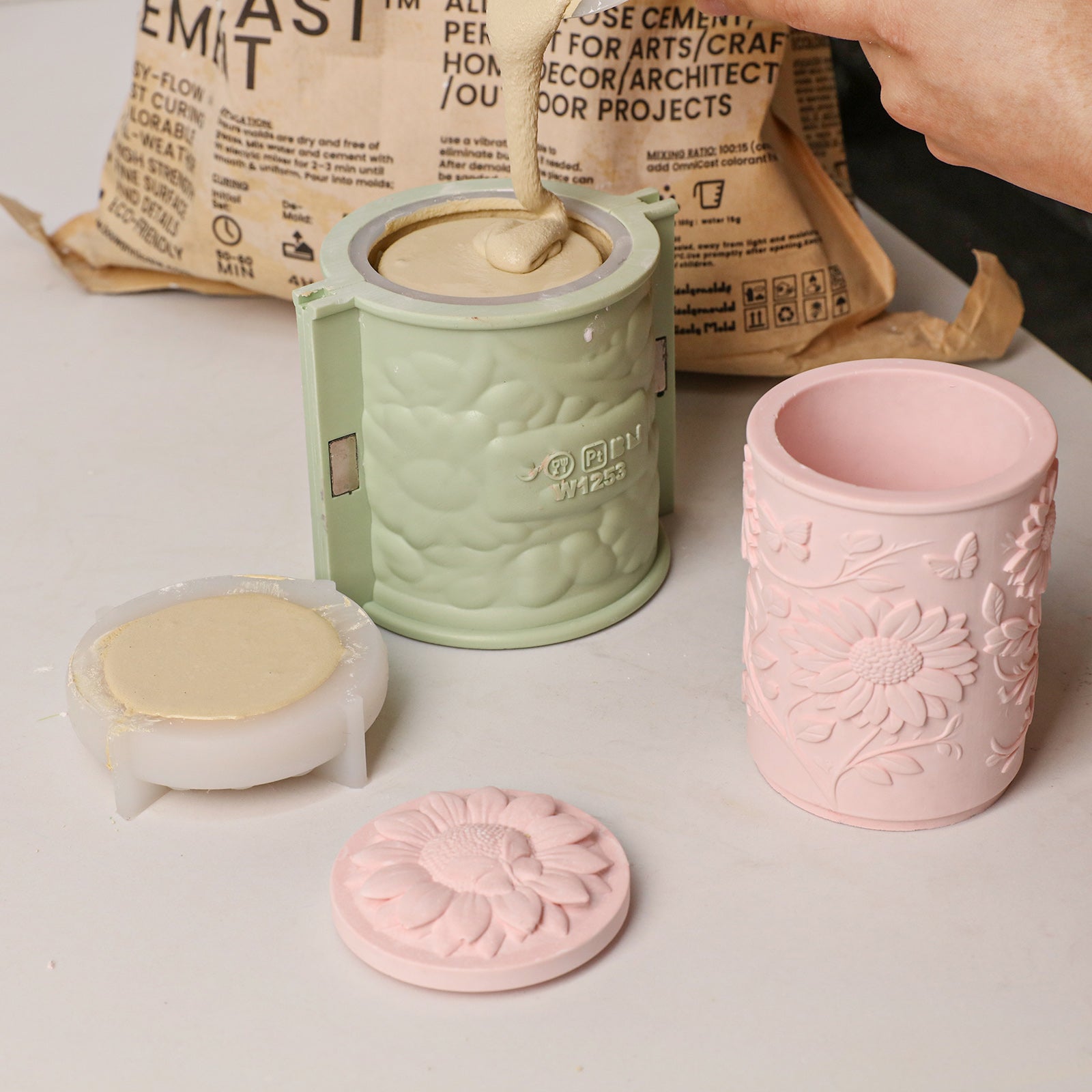 Sunflower Embossed Candle Jar Silicone Mold, pouring cement into mold with pink and beige candle jars - Boowan Nicole