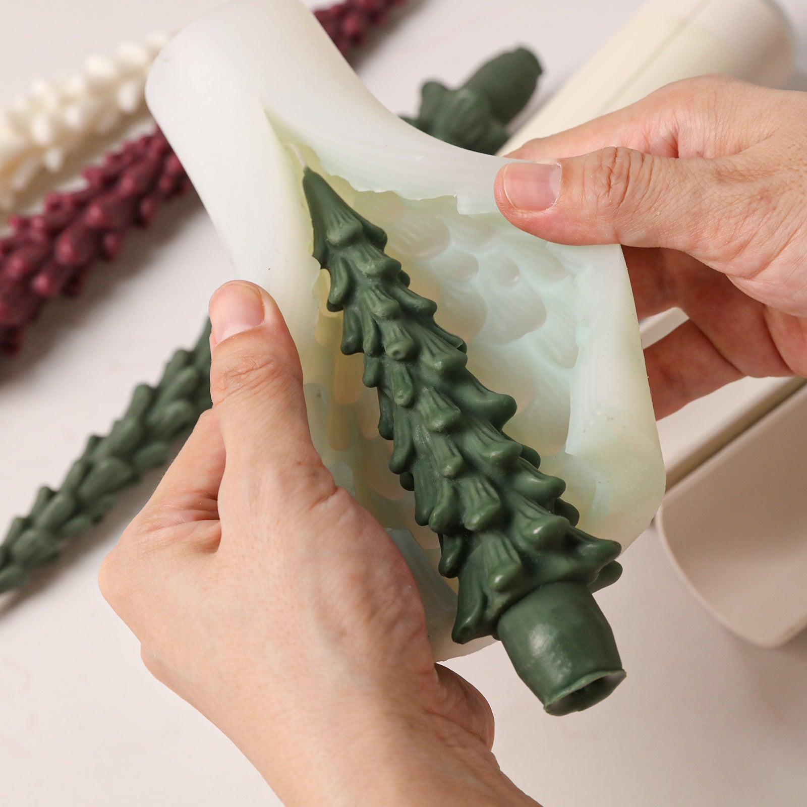 Demolding finished green winter pine taper candle from flexible silicone mold - Boowan Nicole