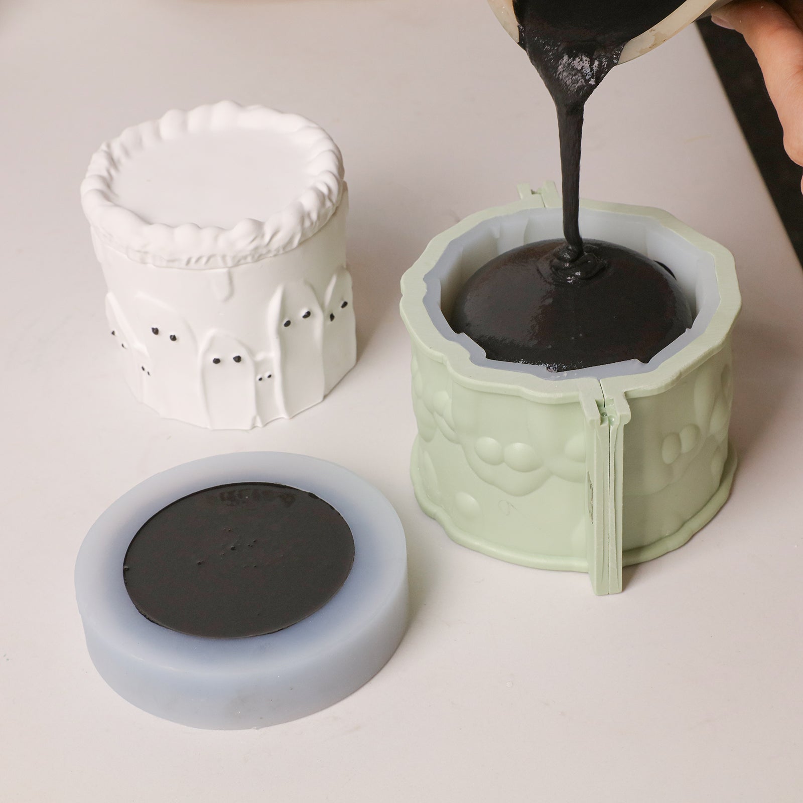 Two-part silicone mold set for ghost cake candle jar, pouring black casting material into the main mold - Boowan Nicole