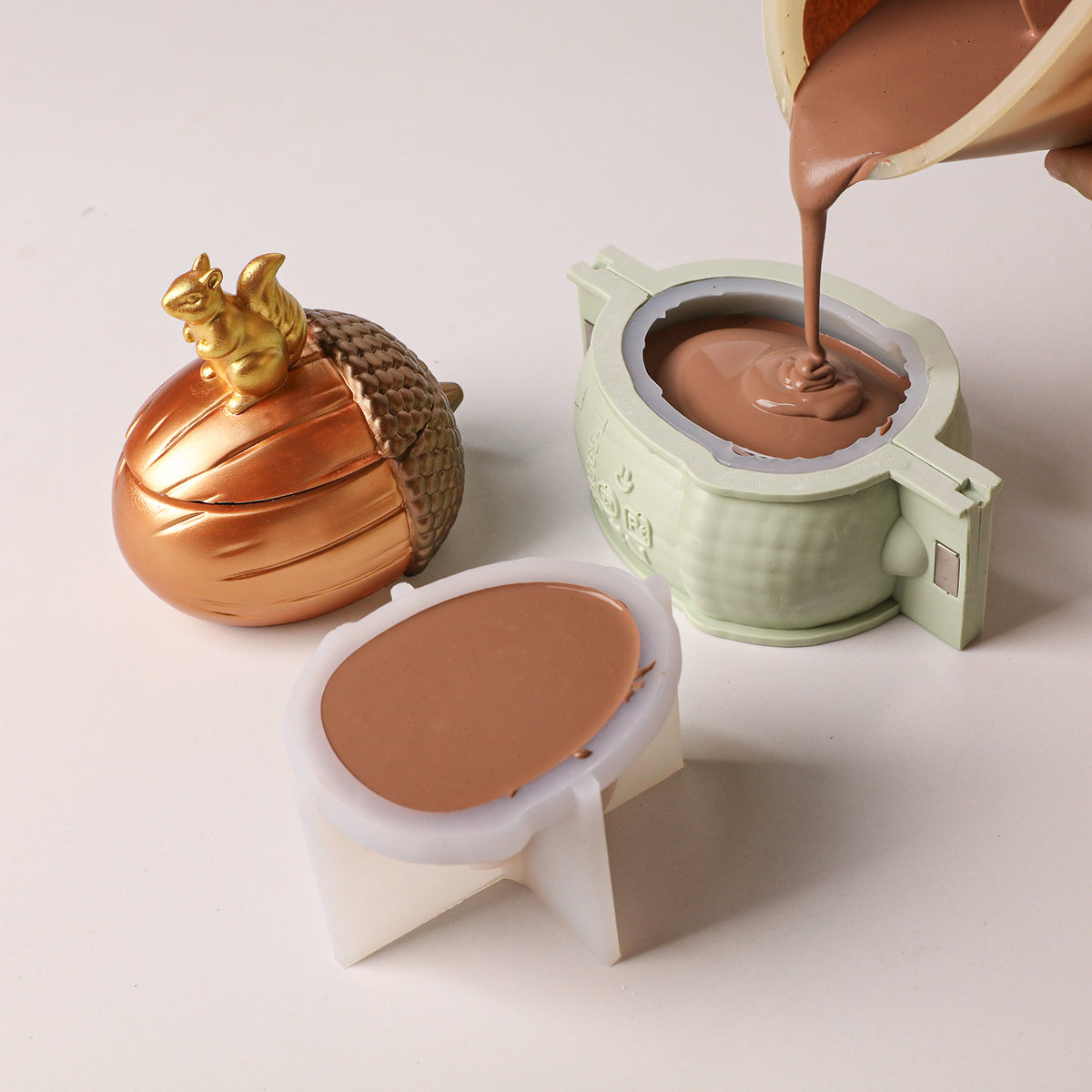 Pouring brown casting liquid into nut candle silicone mold, finished golden squirrel nut candle displayed beside craft supplies - Boowan Nicole