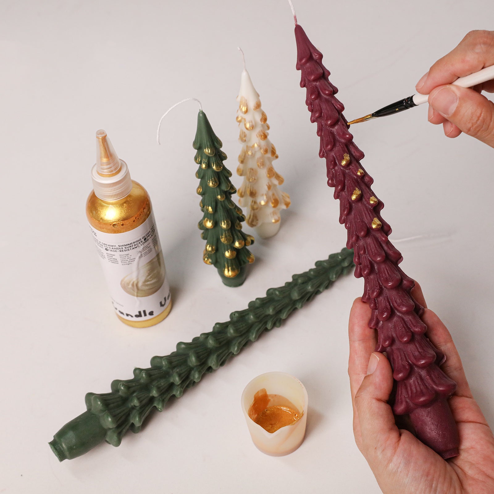 Hand painting gold gilded accents on handmade winter pine taper candles with fine paintbrush - Boowan Nicole