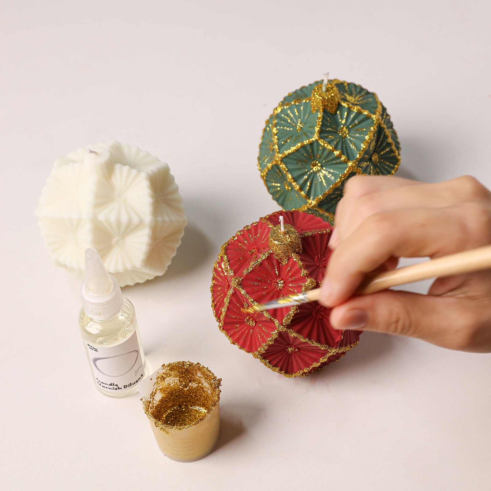 Hand applying gold glitter decorative accents onto handmade geometric bauble candle - Boowan Nicole