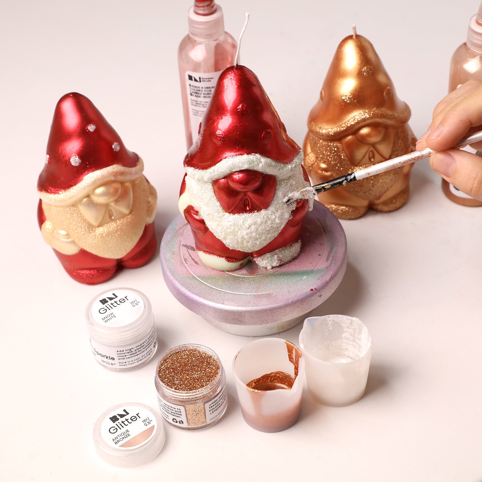 Decorating gnome candle with glitter powder and varnish on craft worktable - Boowan Nicole