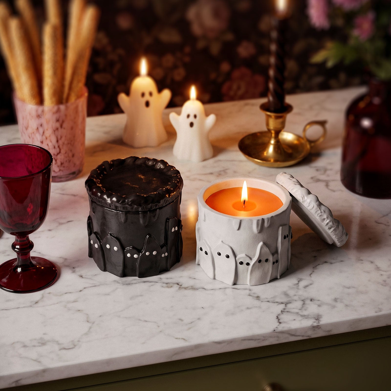 Finished black and white ghost cake lidded candle jars lit on marble counter with small ghost candles for Halloween styling - Boowan Nicole