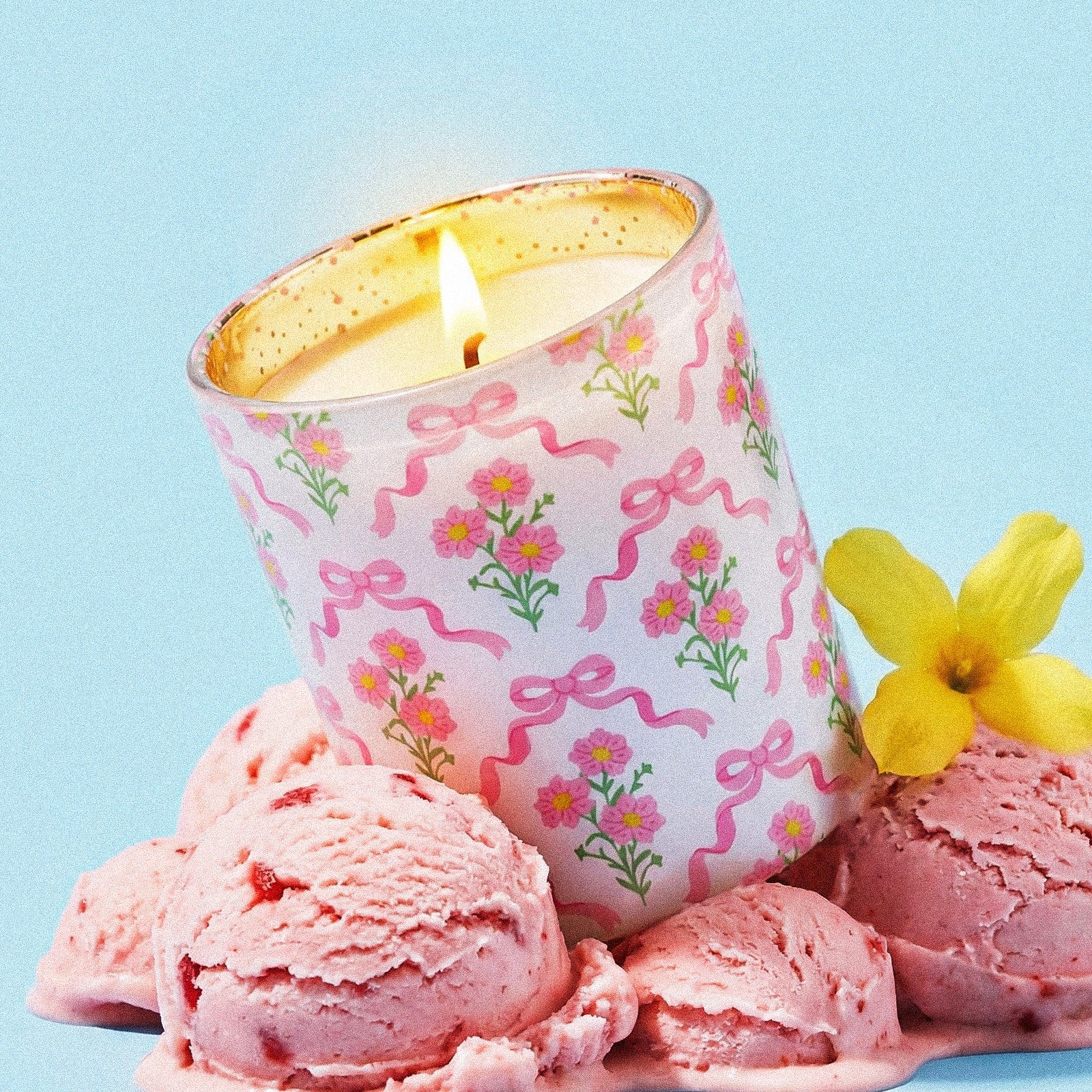 Lit Coquette Bow Daisy Pattern Glass Candle Jar Surrounded by Pink Strawberry Ice Cream Scoops and Fresh Yellow Flower - Boowan Nicole
