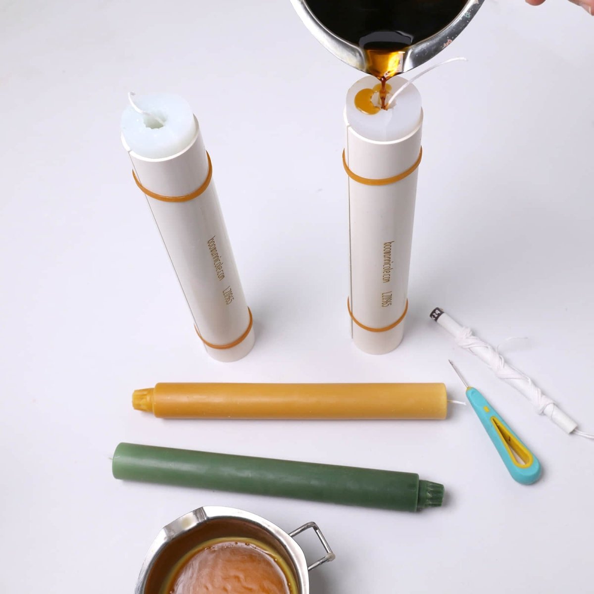 Pouring wax into 9.3" classic taper candle silicone molds, with wicks, tools, and finished candles on the table - Boowan Nicole