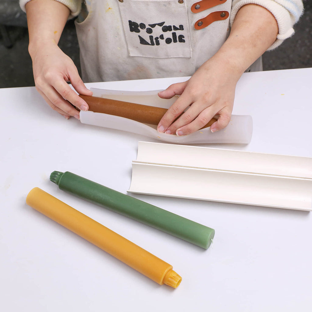 Demolding a brown taper candle from a silicone mold with a support shell - Boowan Nicole