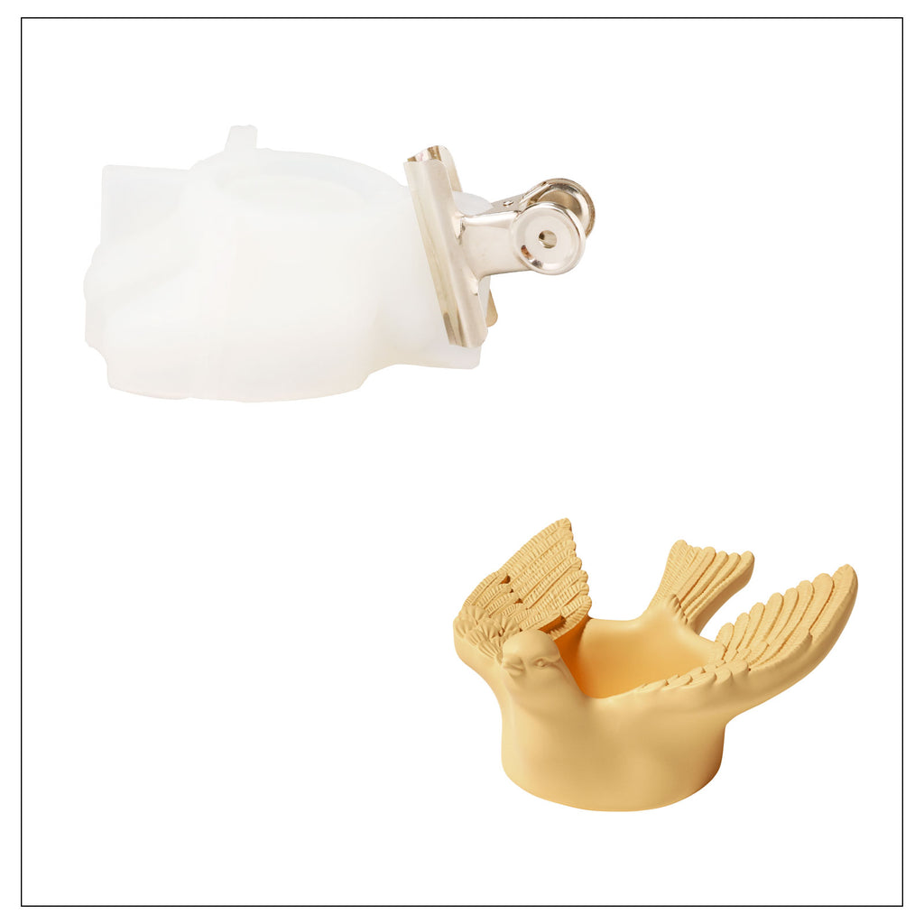Composition featuring a yellow, wing-opened bird-shaped tea light holder alongside a silicone mold, underscoring the crafting process.