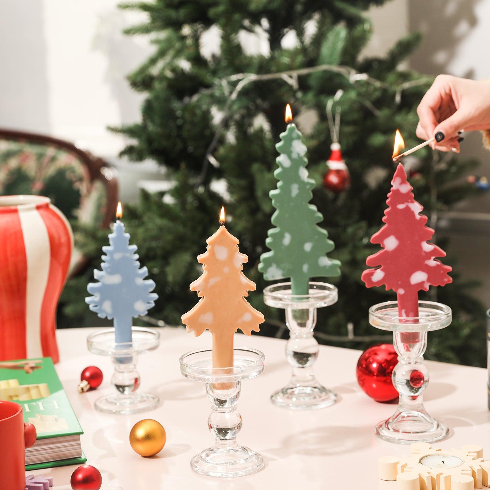 Light a Christmas tree-shaped taper candle placed in a crystal candle holder.