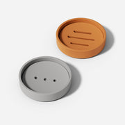 Round soap drain dishes in different shapes in gray and tan colors made using silicone molds.