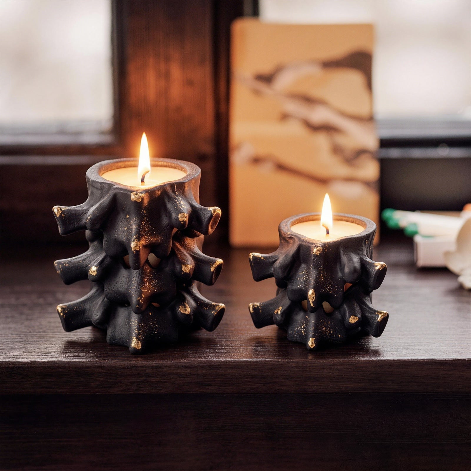 Black Haunted Spine candle jars with gold speckles lit on dark wooden windowsill - Boowan Nicole