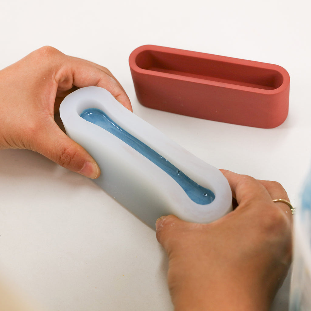 Pour the blue boowannite material into the white silicone mold to create the Long Shaped Post-it Note Holder-Boowan Nicole