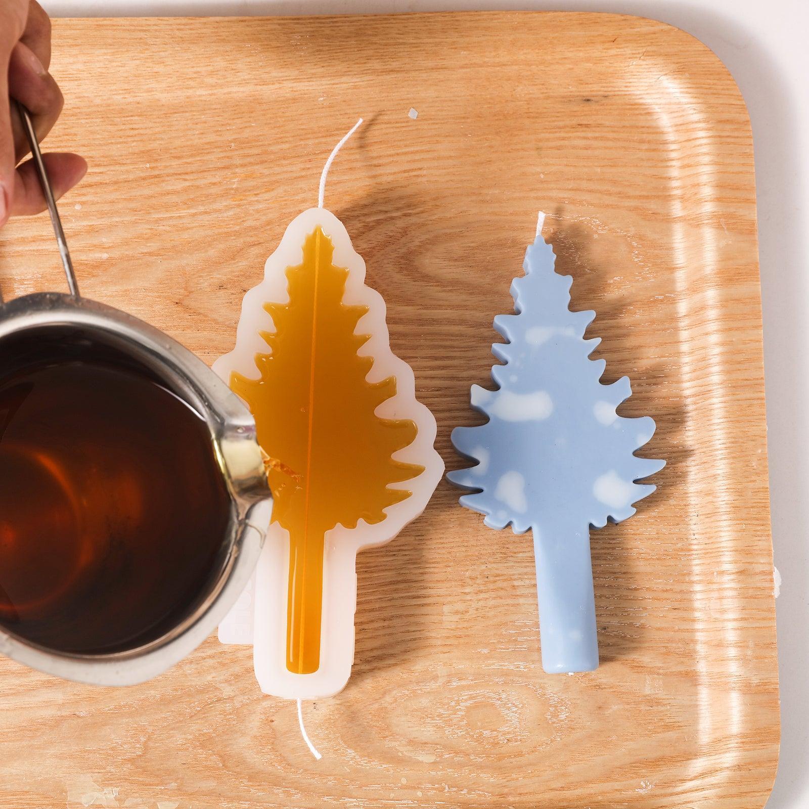 Yellow wax liquid is poured into the silicone mold, and a blue Christmas tree candle with white accents is placed next to it.
