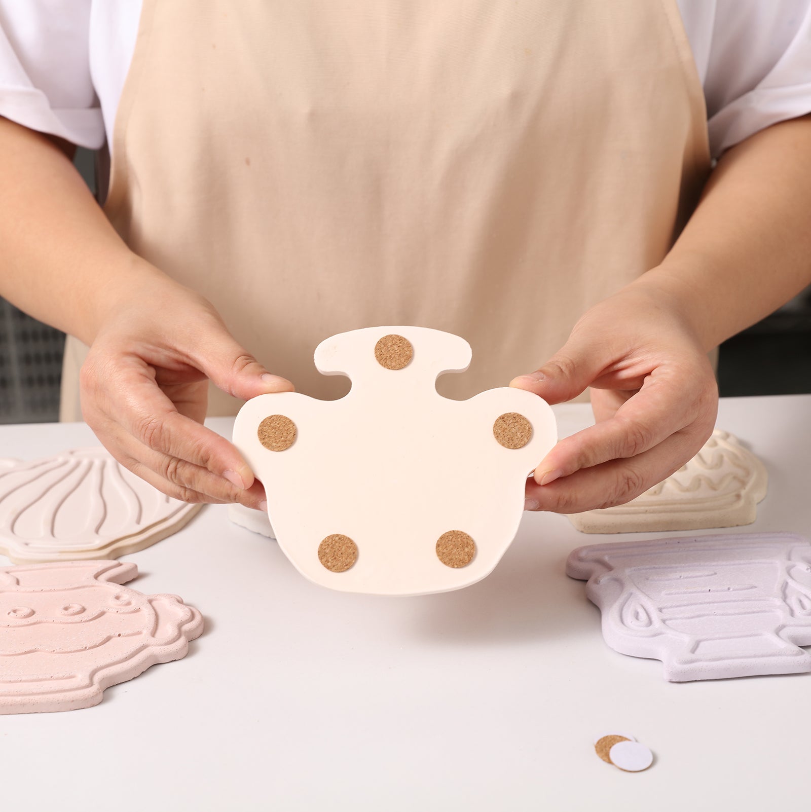 The handheld coaster has a non-slip pad on the back to prevent it from shifting and scratching the table, designed by Boowan Nicole.