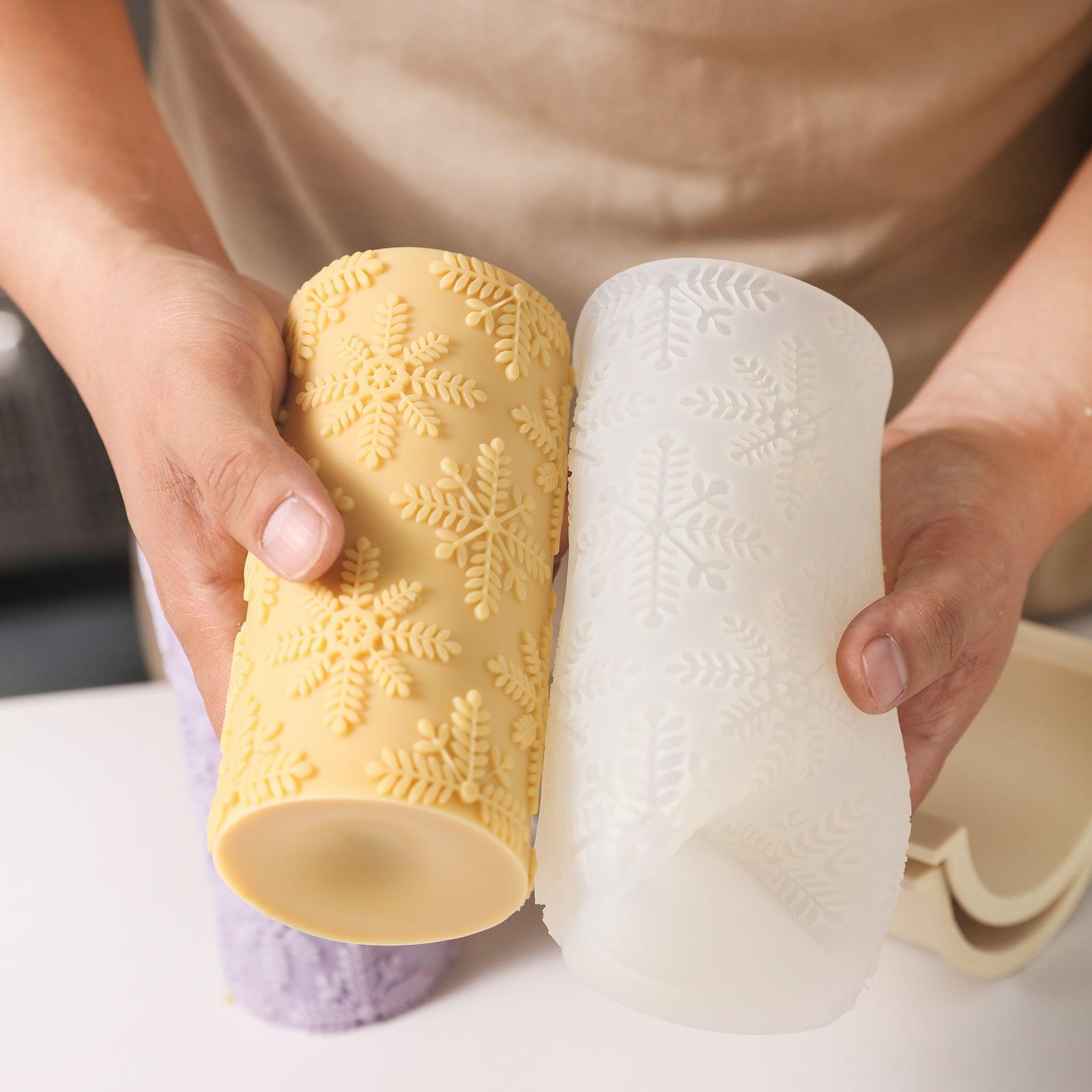 A close-up detail of the yellow long cylindrical snowflake relief candle and the corresponding silicone mold.