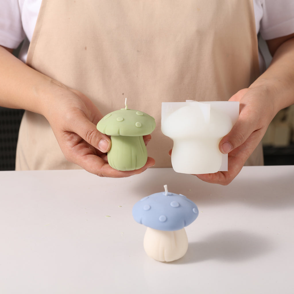 Hand-held display of green toadstool mushroom-shaped candles and corresponding molds, designed by Boowan Nicole.