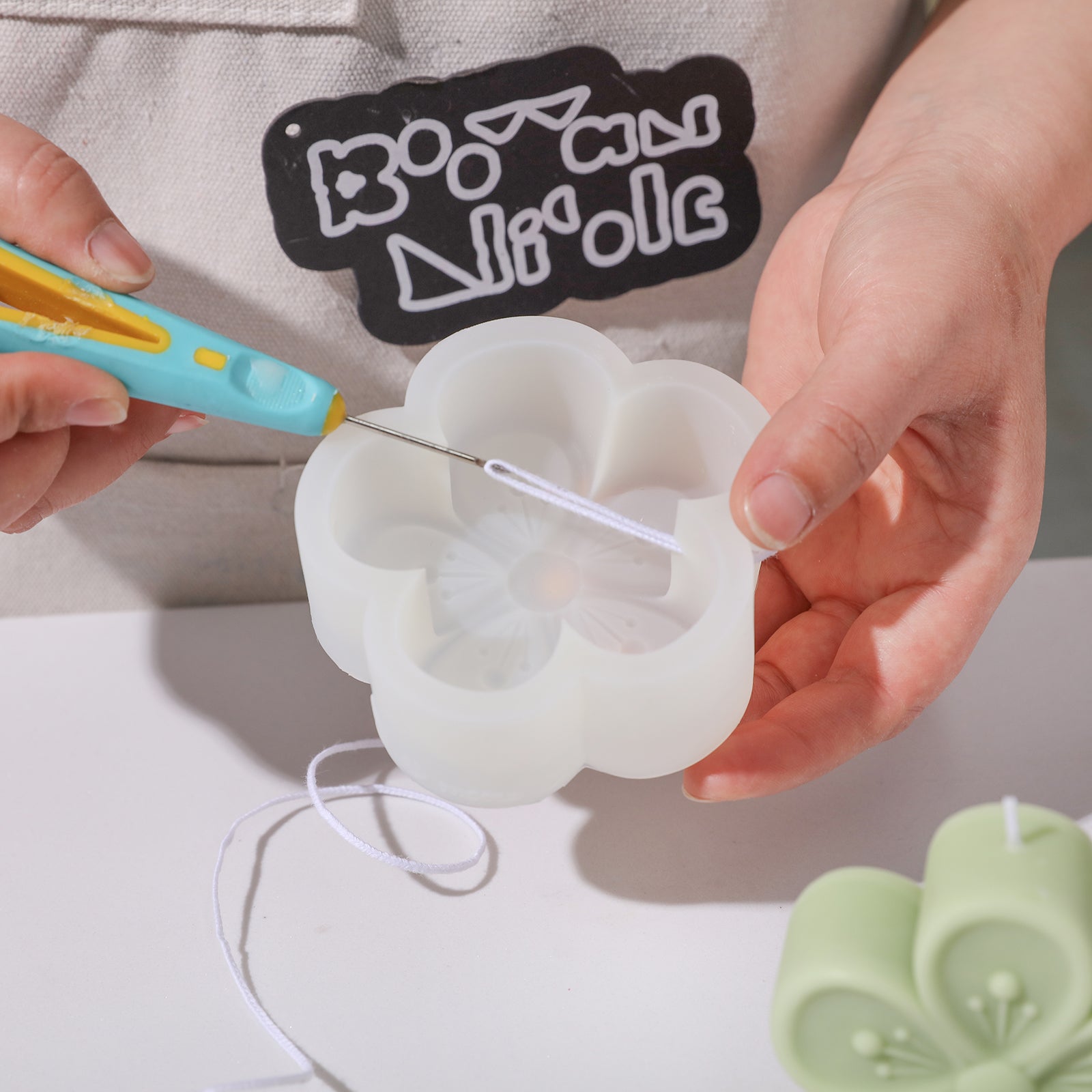 Threading the wax wick from the silicone mold used to make the Peach Blossom Candle - Boowan Nicole