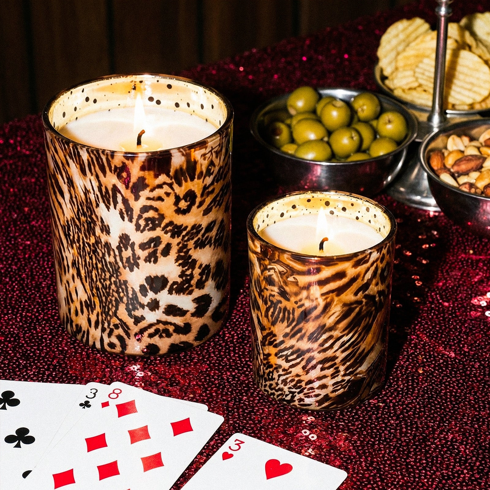 Two Burning Exotic Animal Print Candle Cups Arranged on Red Glitter Tabletop With Snack Plates & Playing Cards - Boowan Nicole