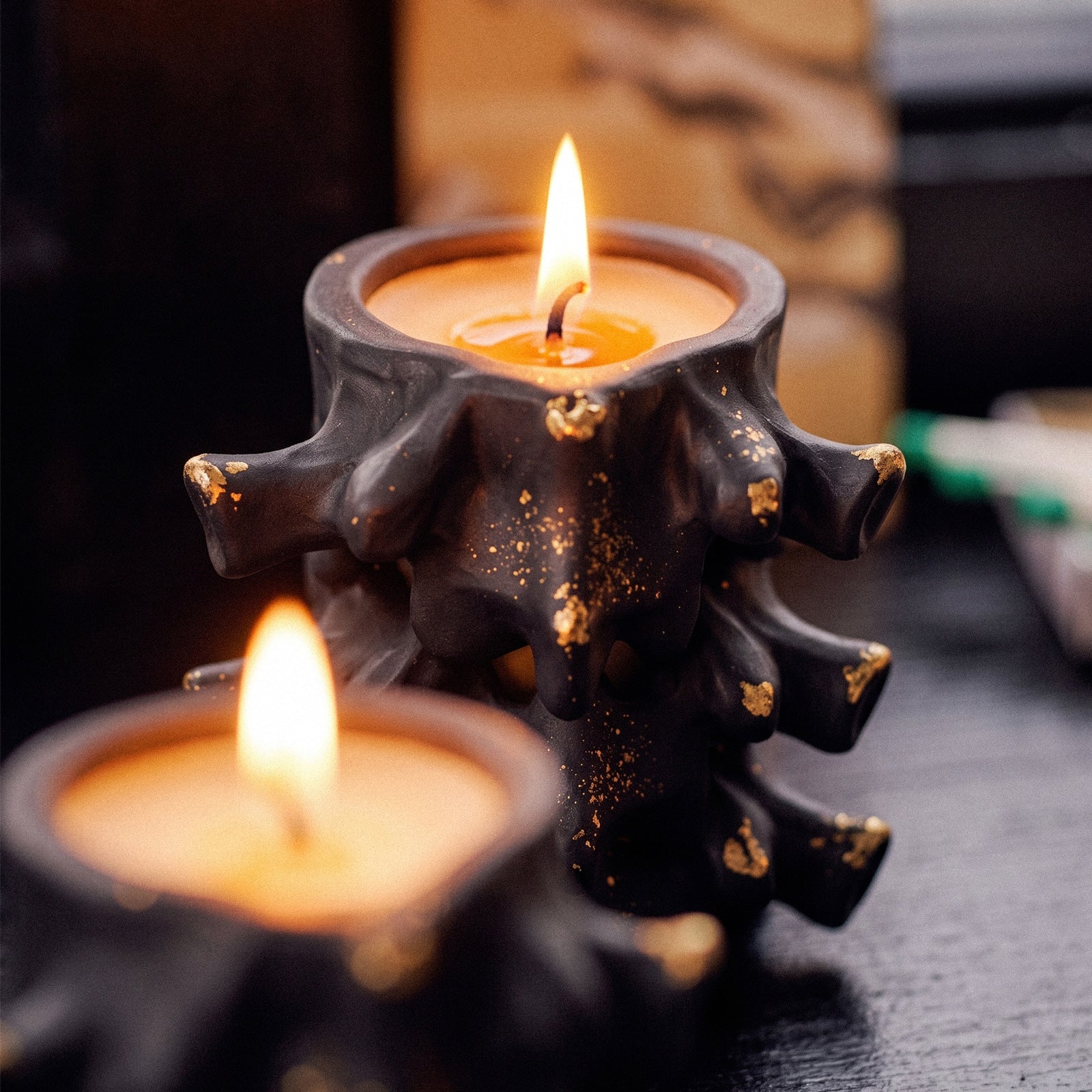 Closeup shot of lit black Haunted Spine candle jar with gold fleck detailing - Boowan Nicole