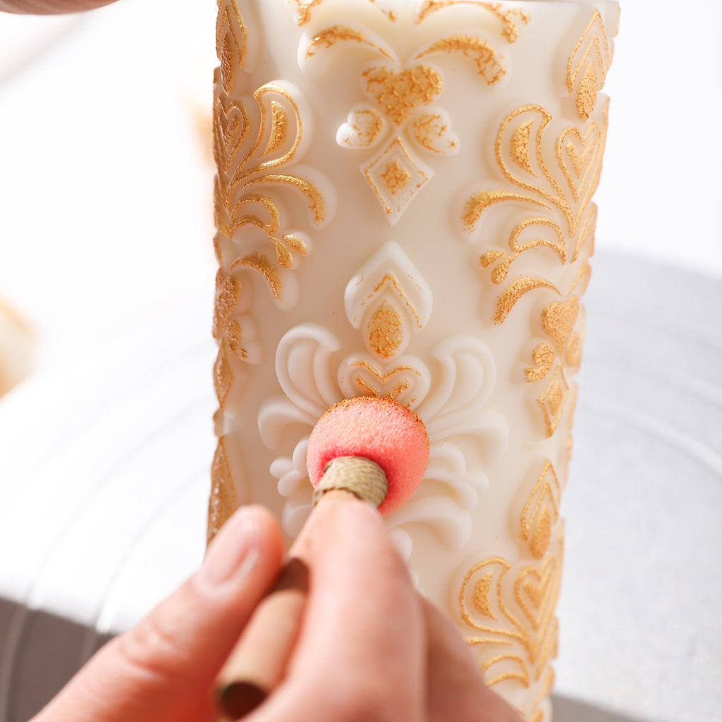 Applying gold mica powder to the white relief patterned candle, creating a unique touch.