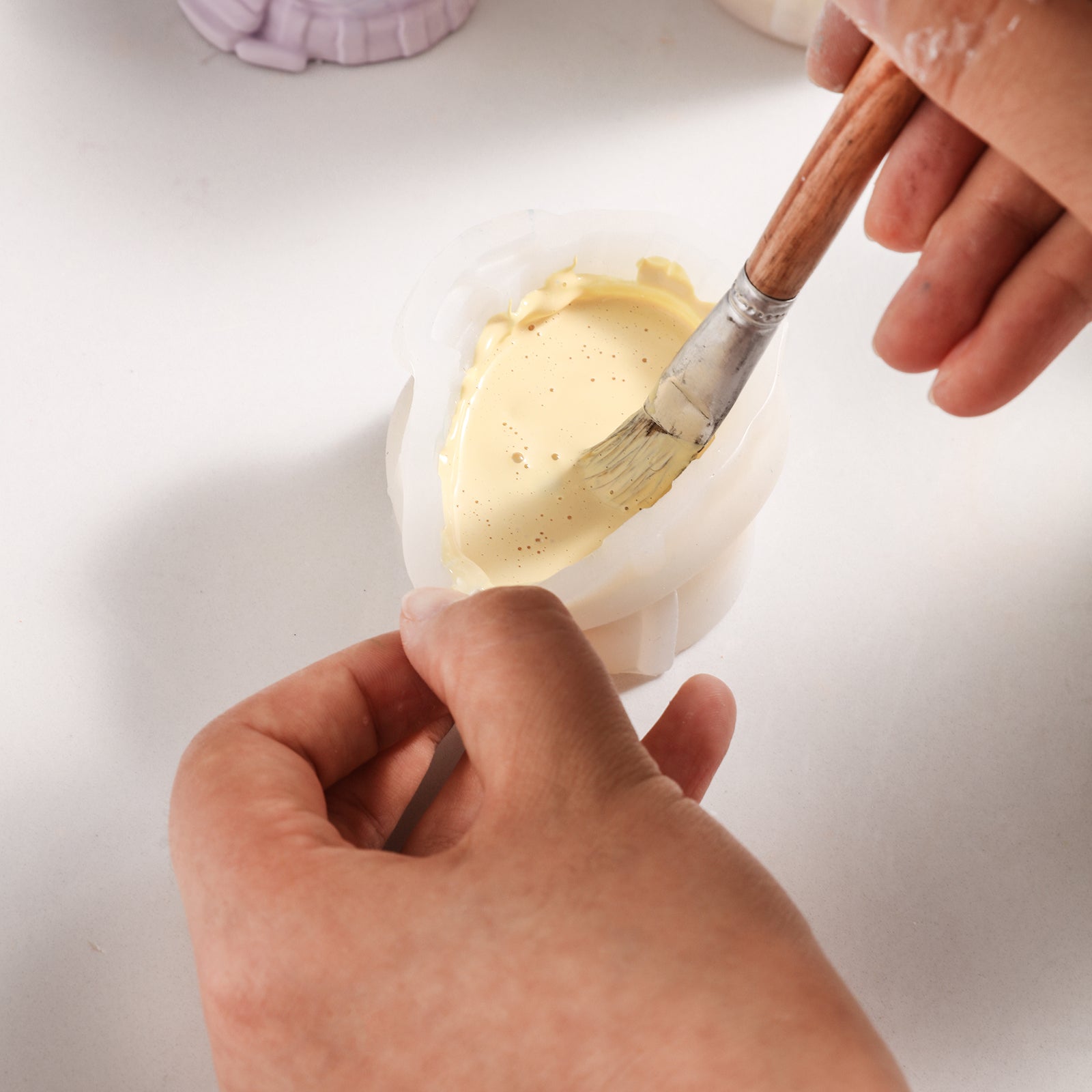 Use a brush to remove air bubbles from the material in the silicone mold to help the piece take shape - Boowan Nicole