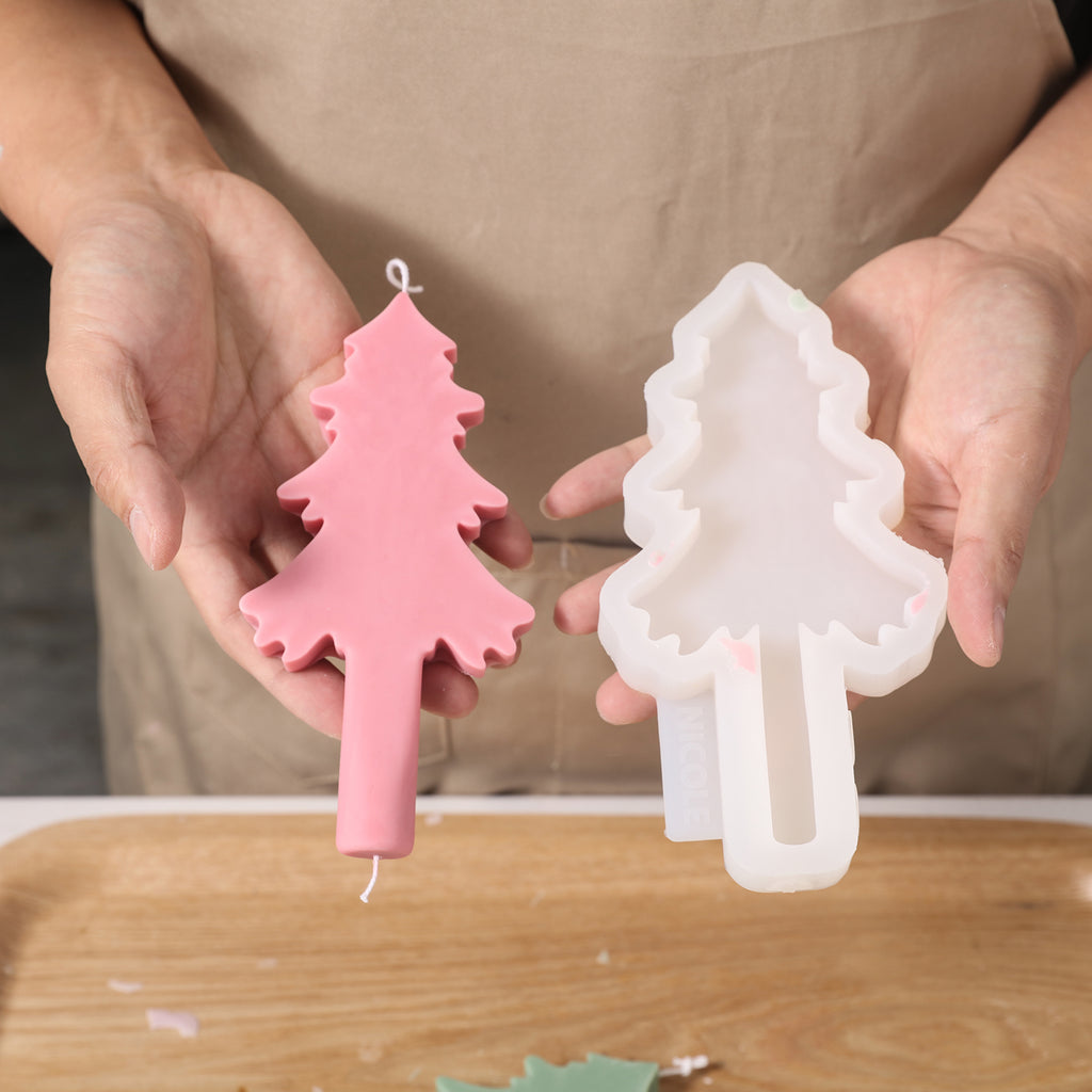 Hand-held display of pink Christmas tree shaped taper candles and silicone molds.