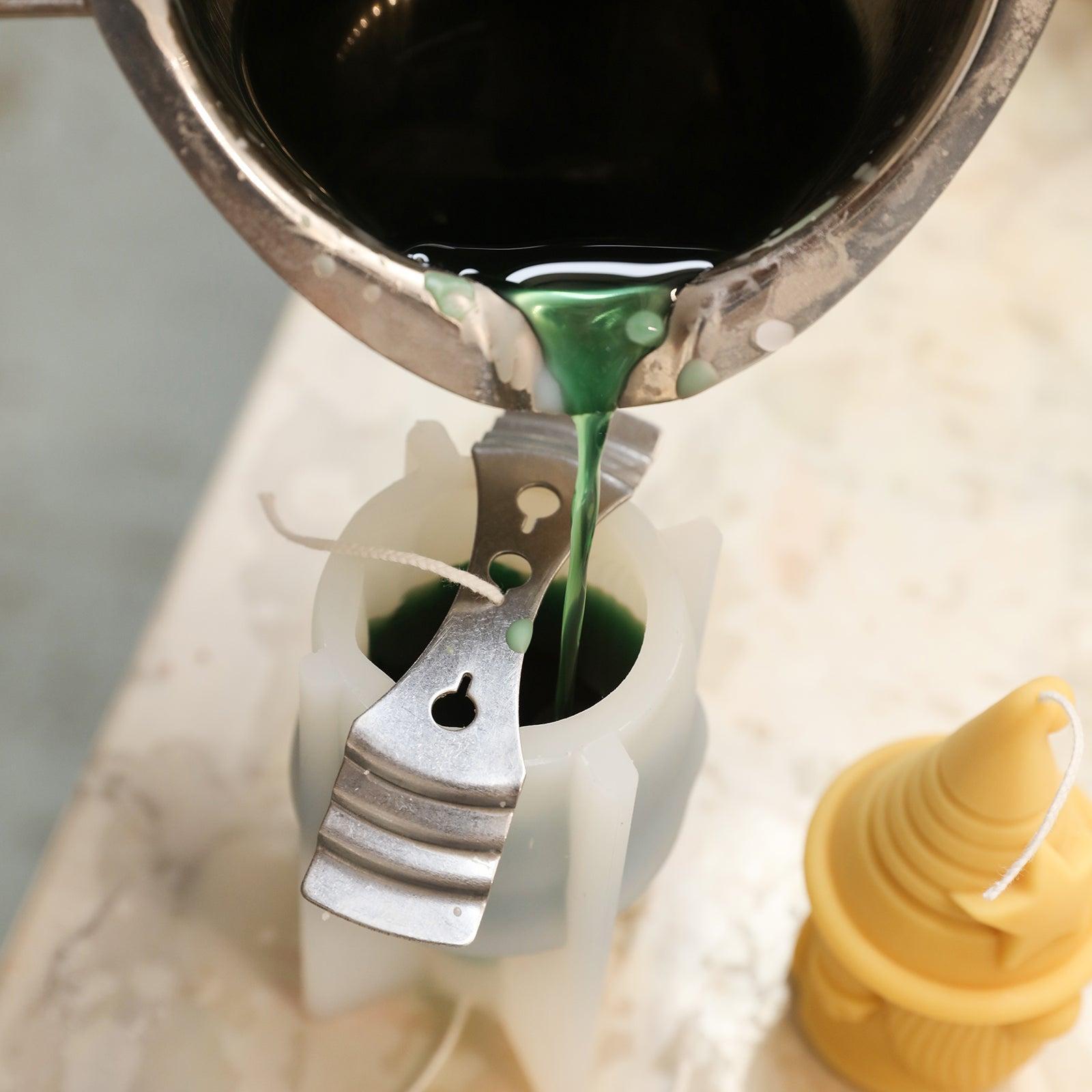 Pour green wax liquid into silicone mold to create Stellan of Hat-tactic Gnome Squad Candle-Boowan Nicole