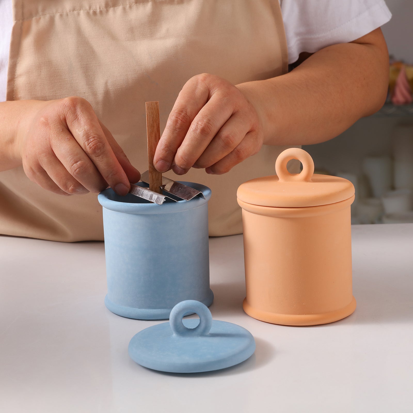 Insert candle wick in blue Cylinder Short Candle Jar next to yellow candle jar -Boowan Nicole