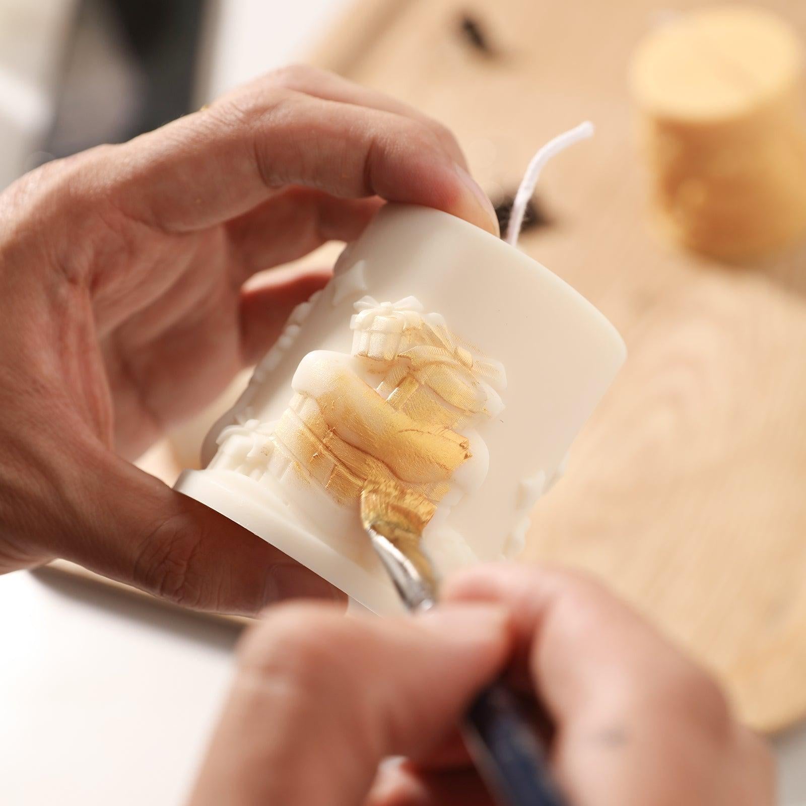 Applying golden mica powder to a white Christmas gift pattern embossed pillar candle adds to the beauty of the candle - Boowan Nicole