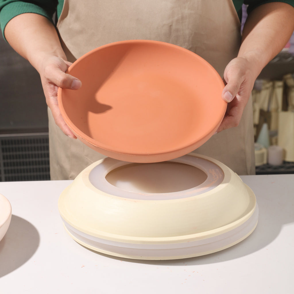 A large round tray made using silicone molds is displayed in hand, and a silicone mold making kit is placed on the table below.