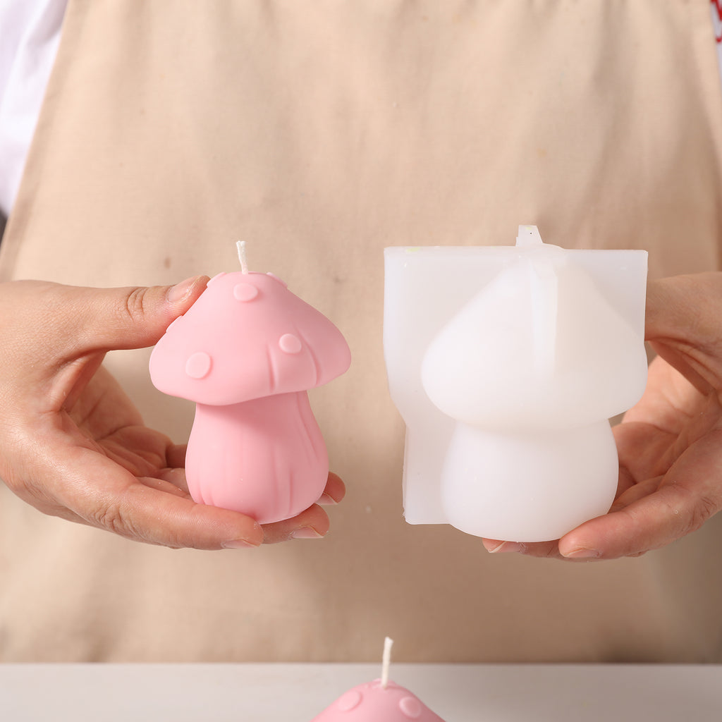 Hand-held display of pink fungus mushroom-shaped candles and corresponding silicone molds, designed by Boowan Nicole.