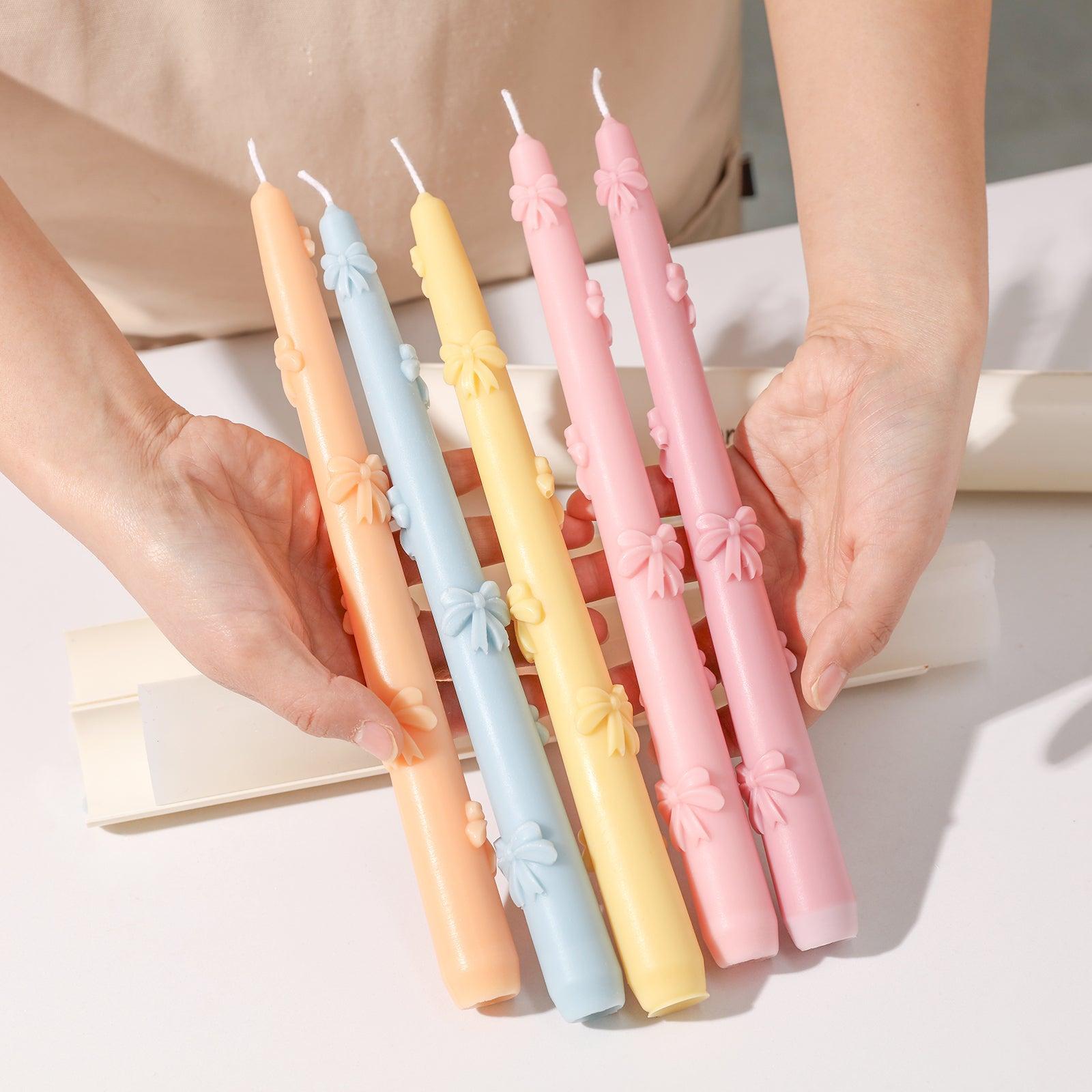 A vibrant display showcasing Ribbon Bow Taper Candles in various colors, each adorned with an intricate bow design.