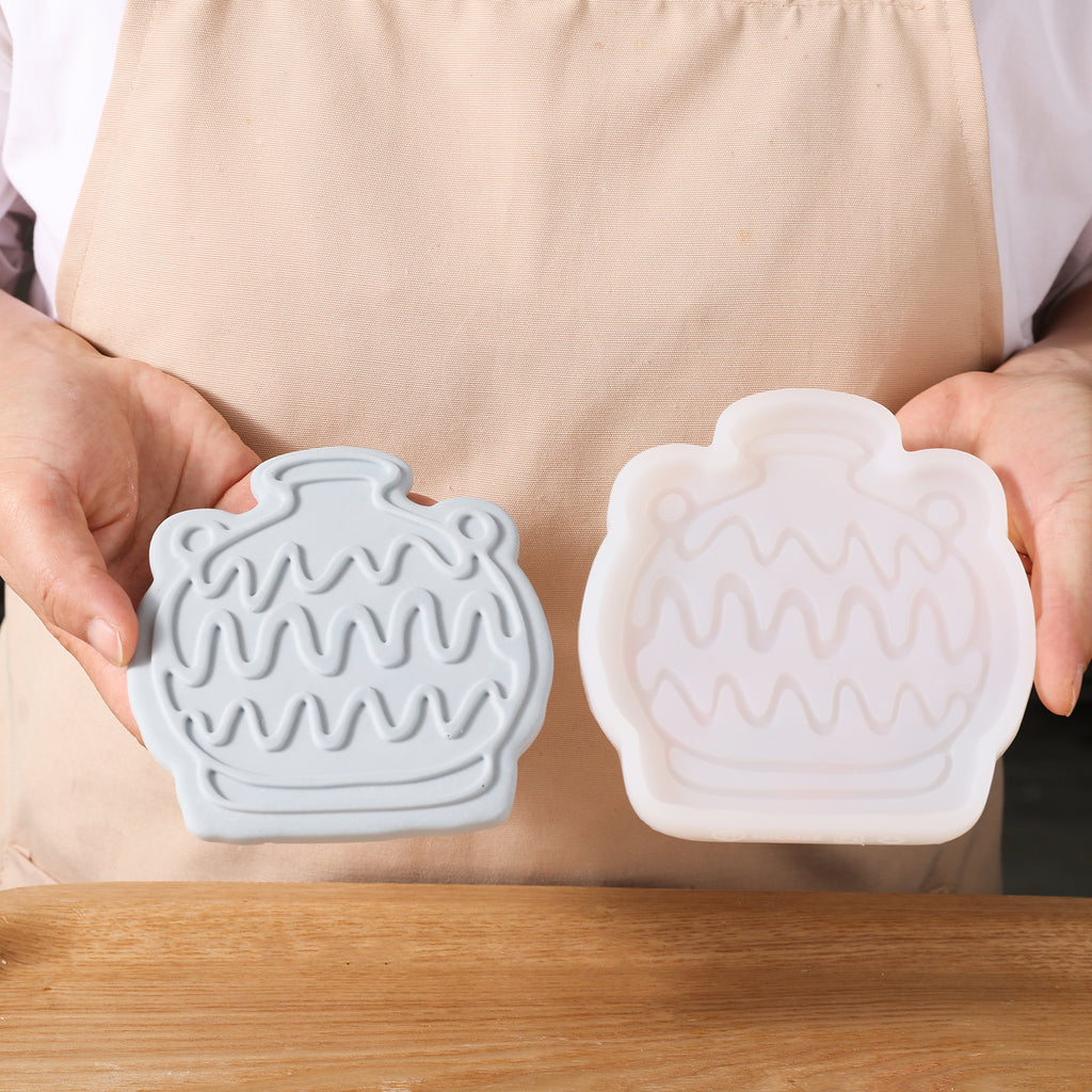 Hand-held display with gray amphora-shaped coaster and white silicone mold, designed by Boowan Nicole.