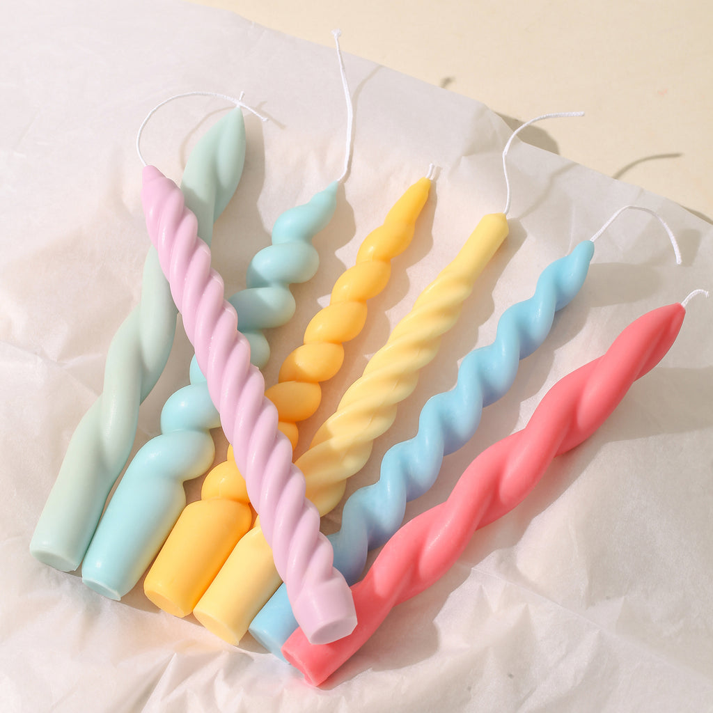 Crafted with precision using Boowannicole's silicone molds, an array of vibrantly shaped taper candles elegantly rests on the tabletop. The unique designs radiate brilliance, showcasing the beauty of the brand's creativity.
